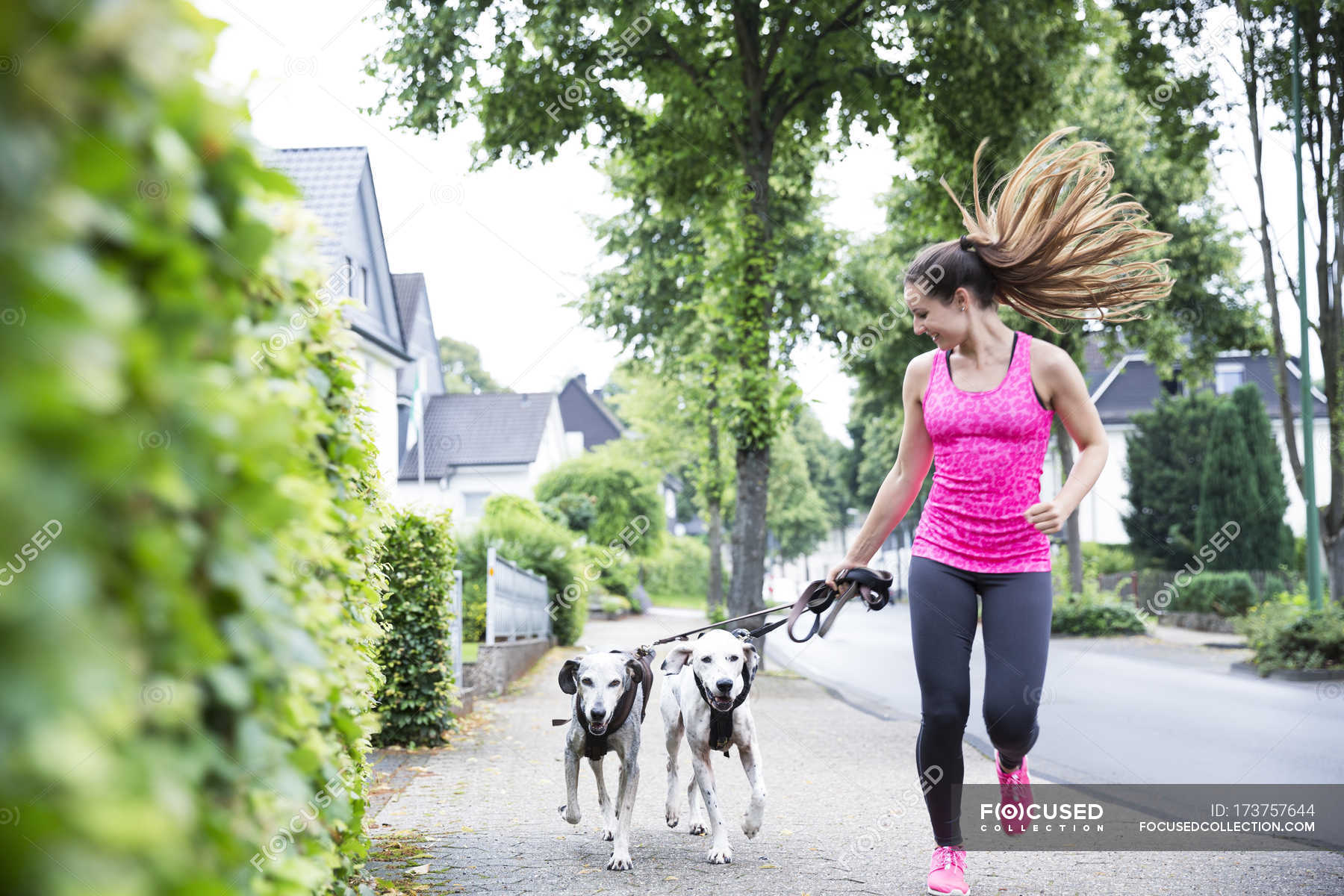 Young woman jogging with two dogs — sport, confidence Stock Photo