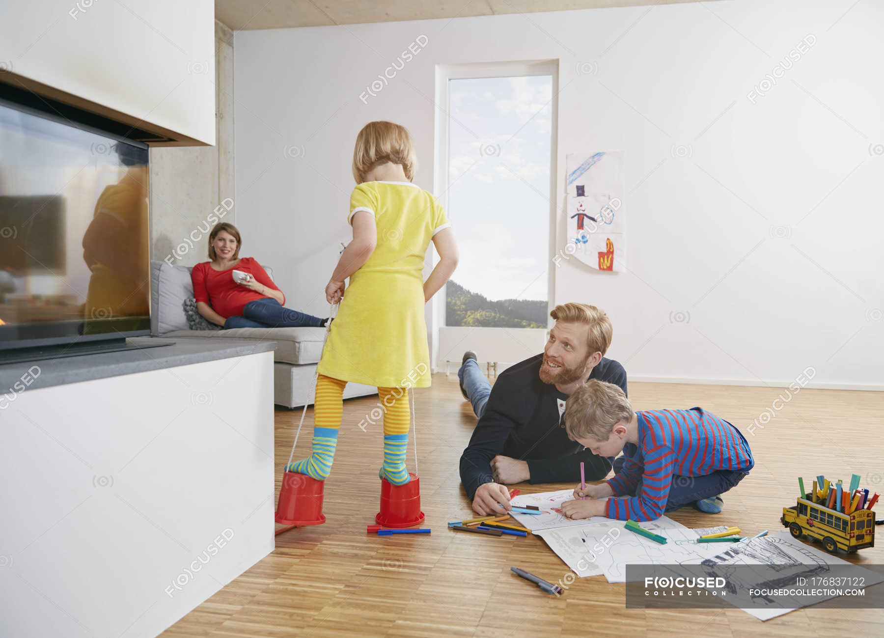 Father And Son Drawing On Floor While Mother And Daughter Having