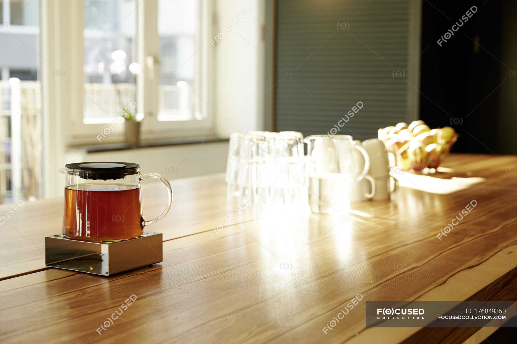 Teapot on teapot warmer on tabletop in a modern office — indoor, wood