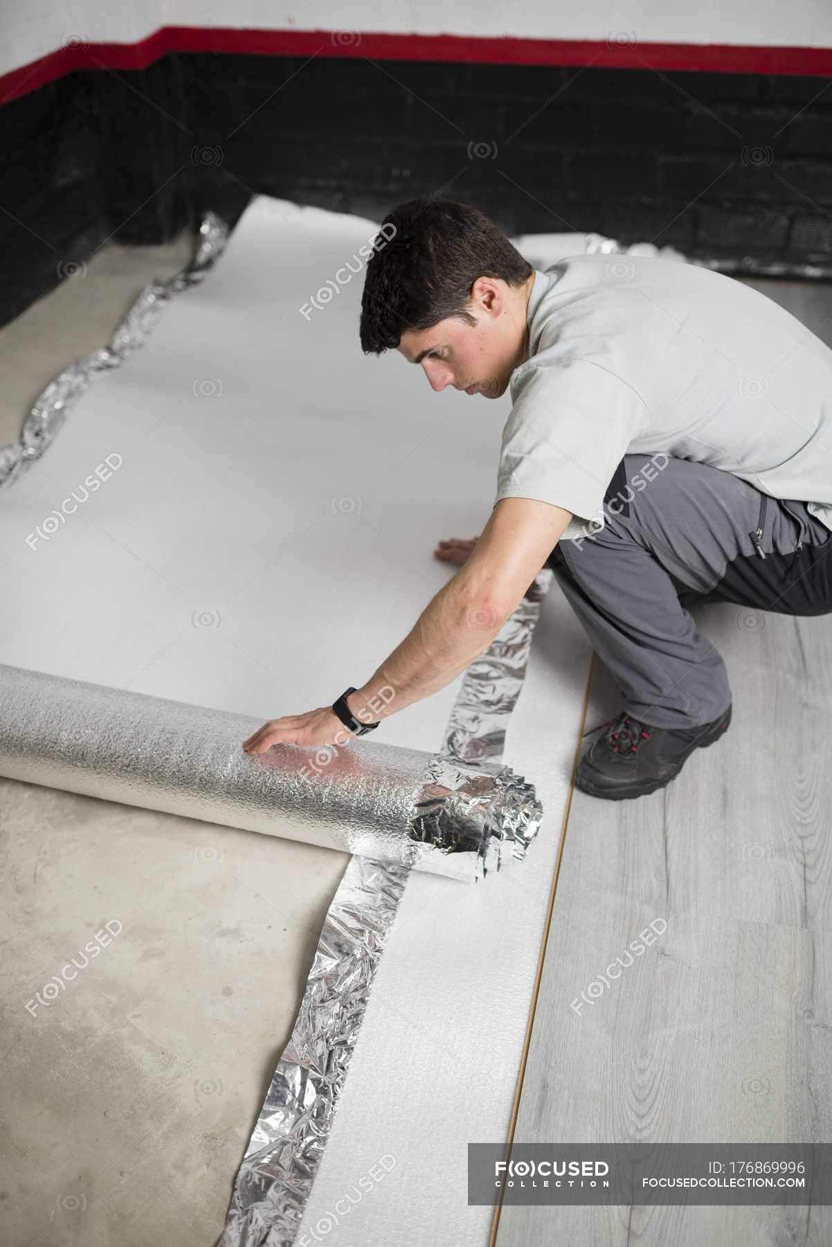 Young Man Placing A Insulating Material For A Laminate Flooring Caucasian Appearance Rebuilding Stock Photo