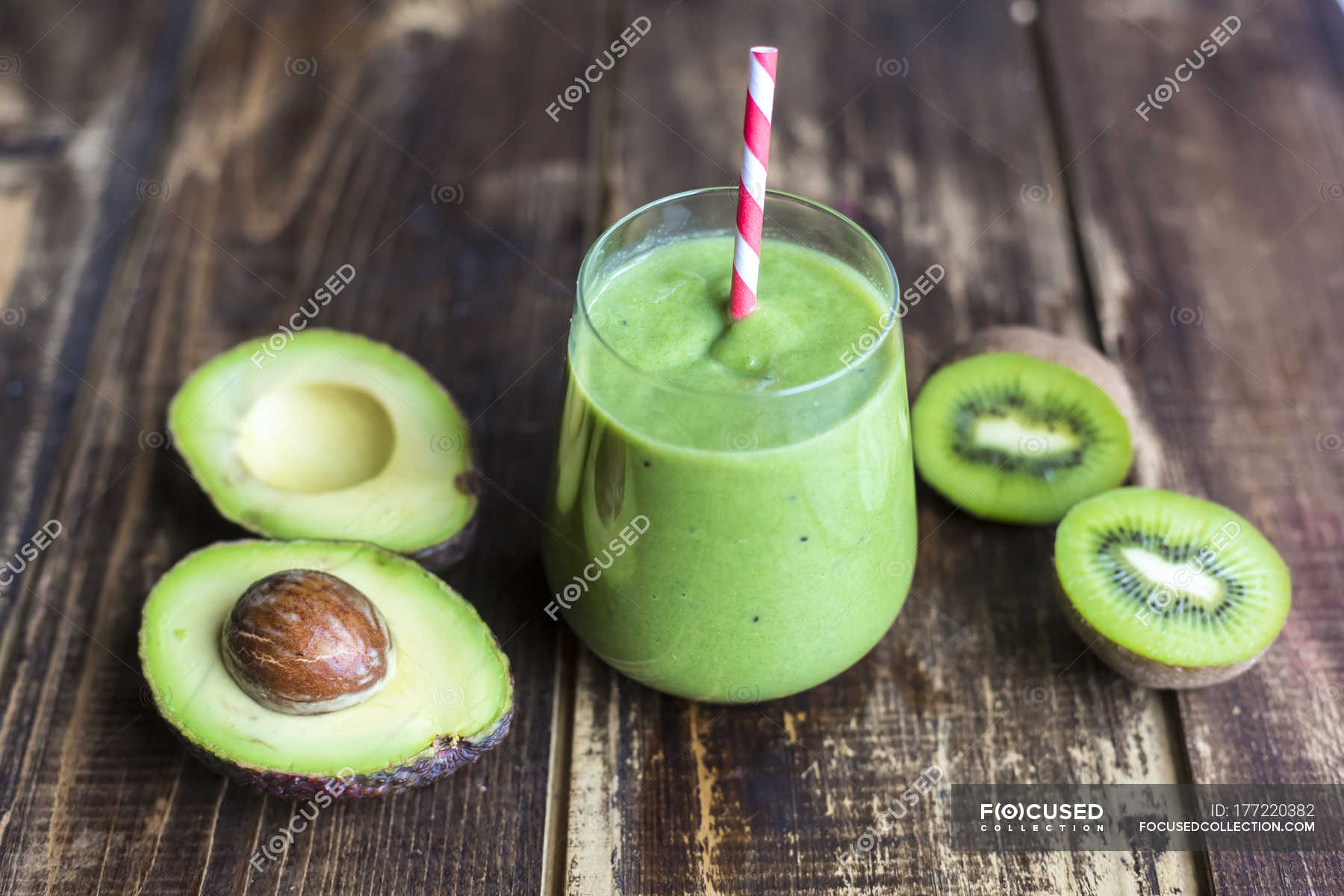 Glass of avocado kiwi smoothie and sliced fruits on wood — drinking straw,  green smoothie - Stock Photo | #177220382