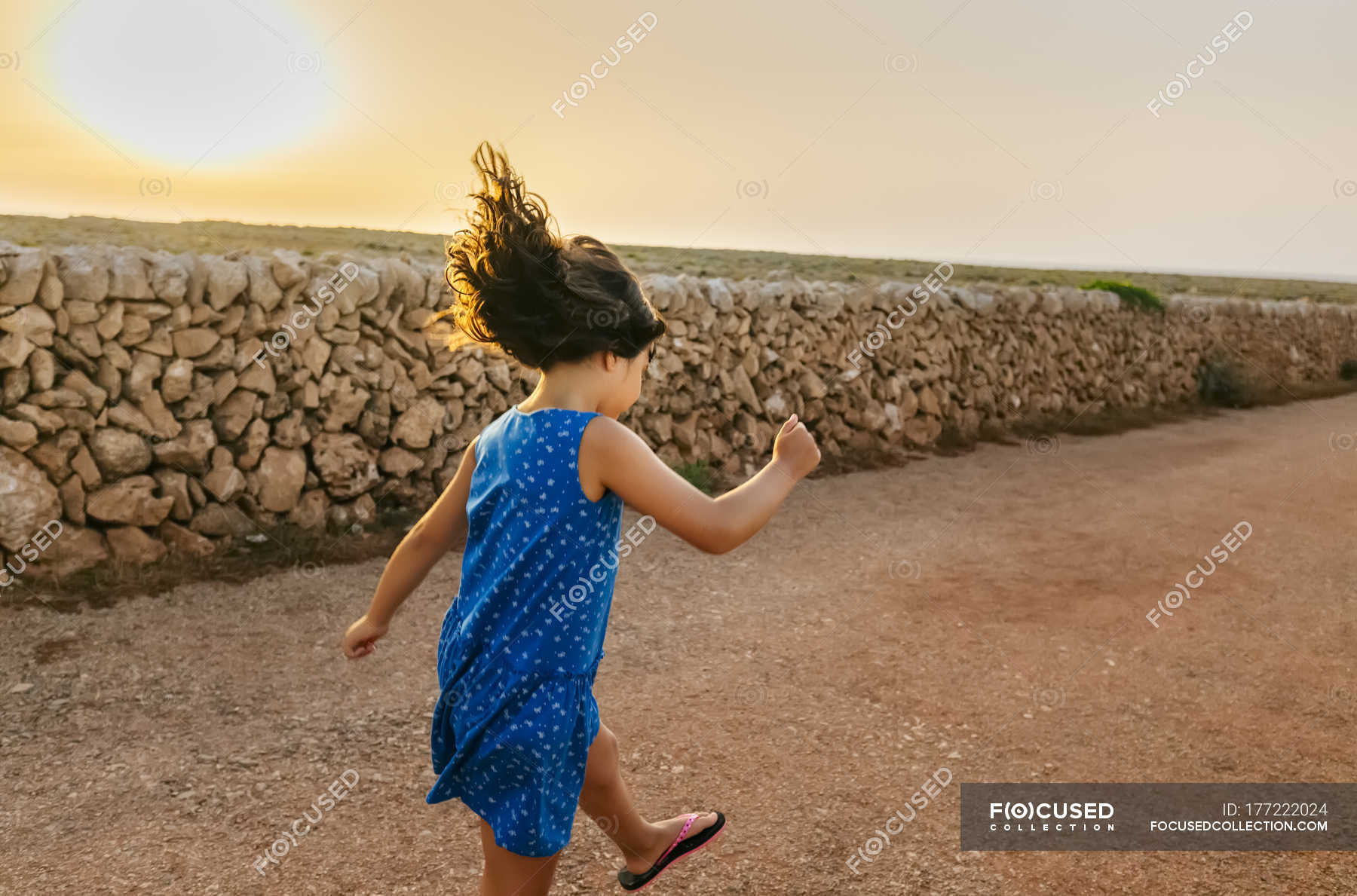 Bambina che salta sulla strada al tramonto — Capelli castani, Lancio ...