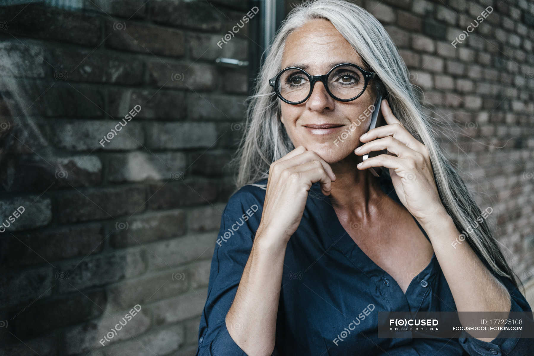 smiling-woman-with-long-grey-hair-on-cell-phone-on-the-phone-indoor