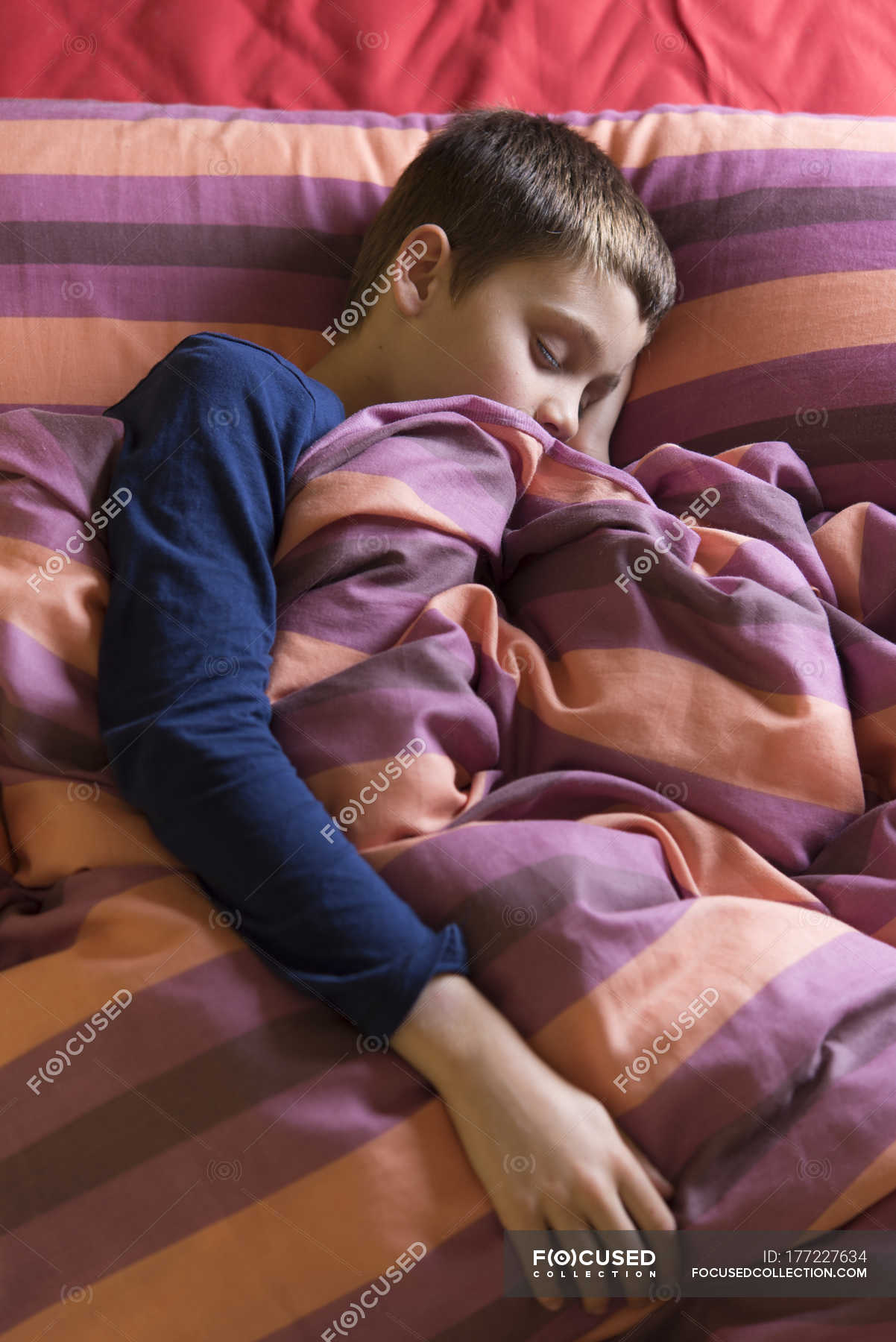 boy-sleeping-in-bed-under-striped-blanket-childhood-lying-down