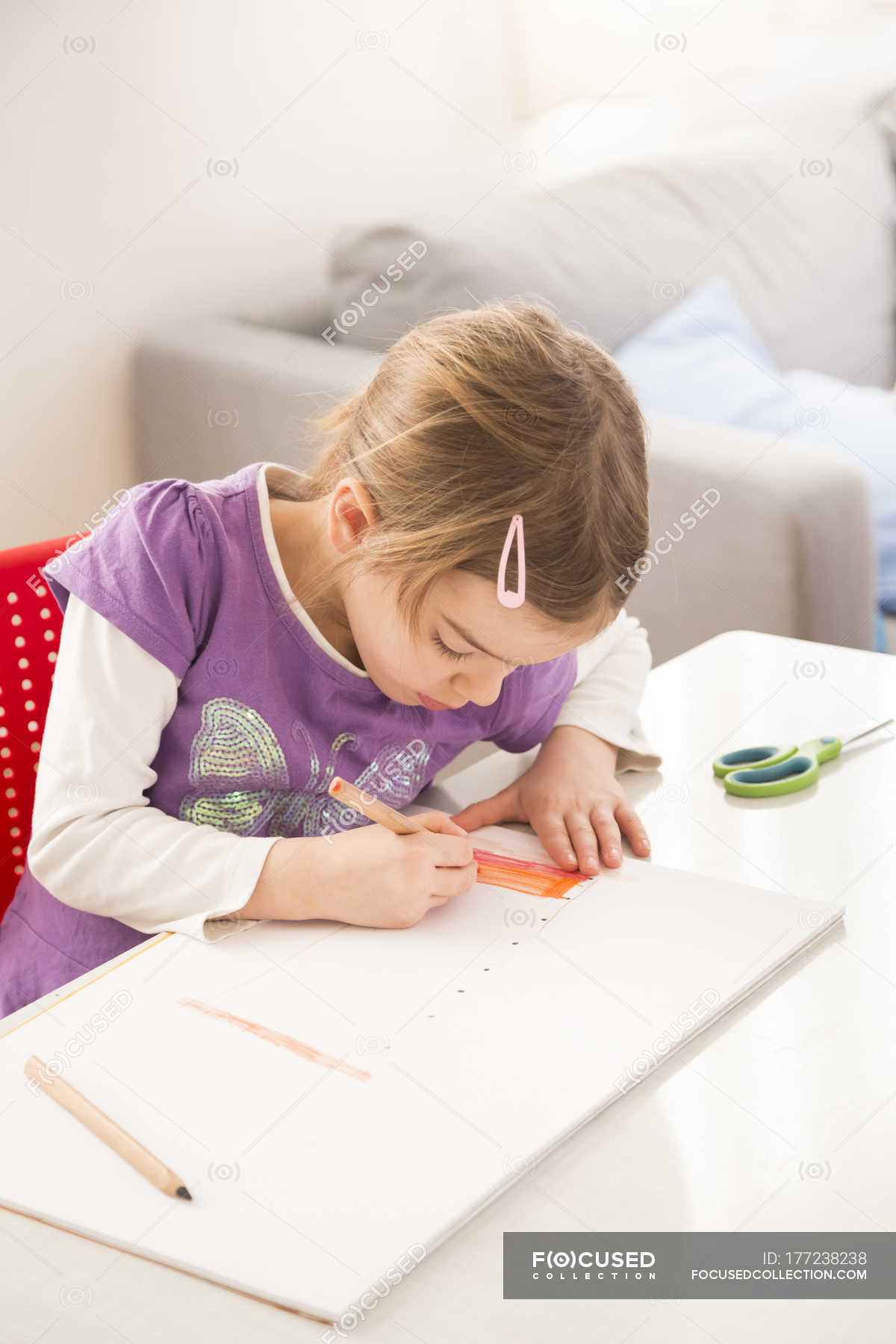 Little Girl Drawing On Sheet Of Paper At Desk Table Learning
