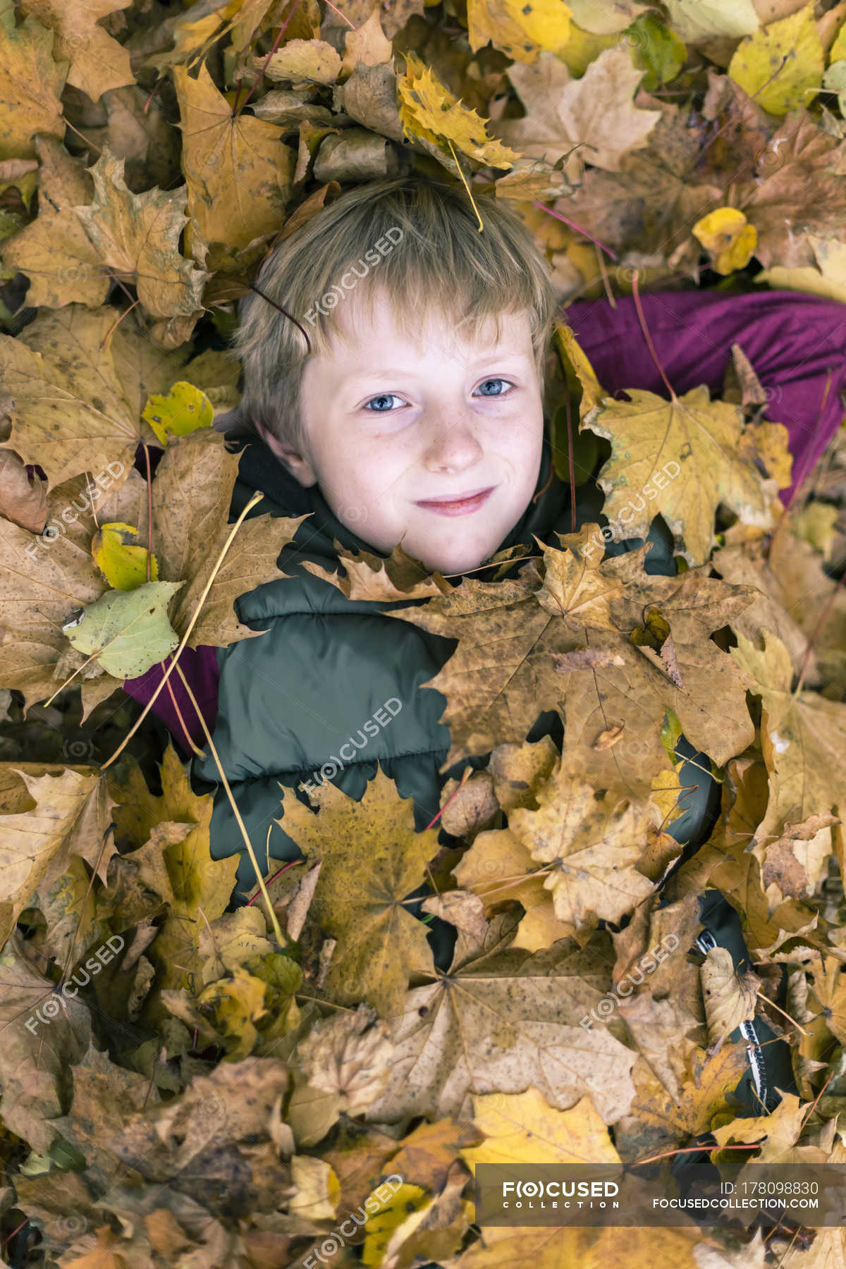 portrait-of-boy-lying-on-the-ground-covered-with-autumn-leaves