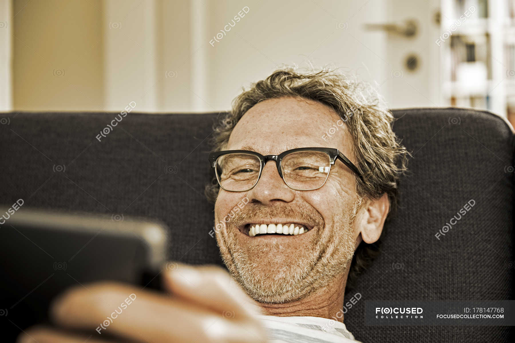 portrait-of-laughing-man-lying-on-the-couch-using-tablet-confidence