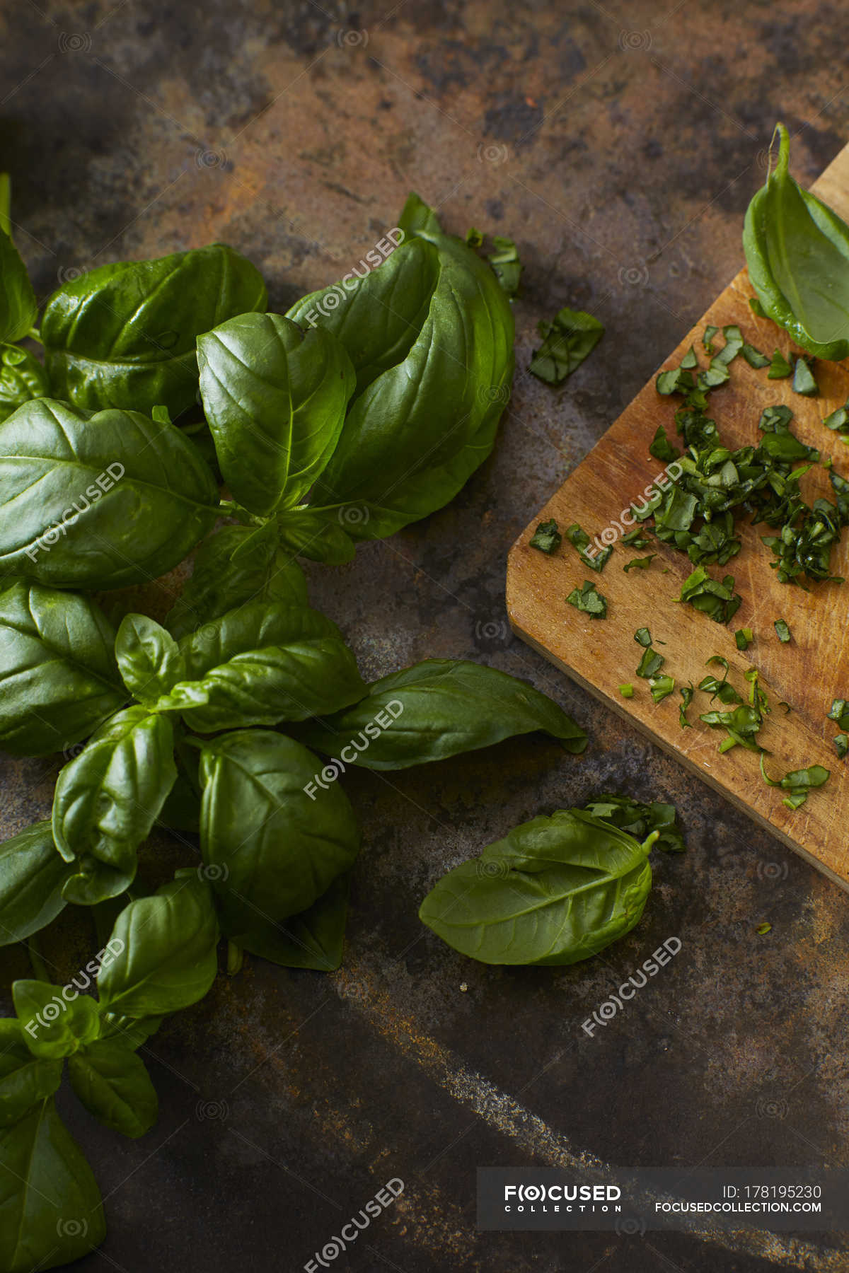 Whole and chopped basil leaves — background, rustic Stock Photo