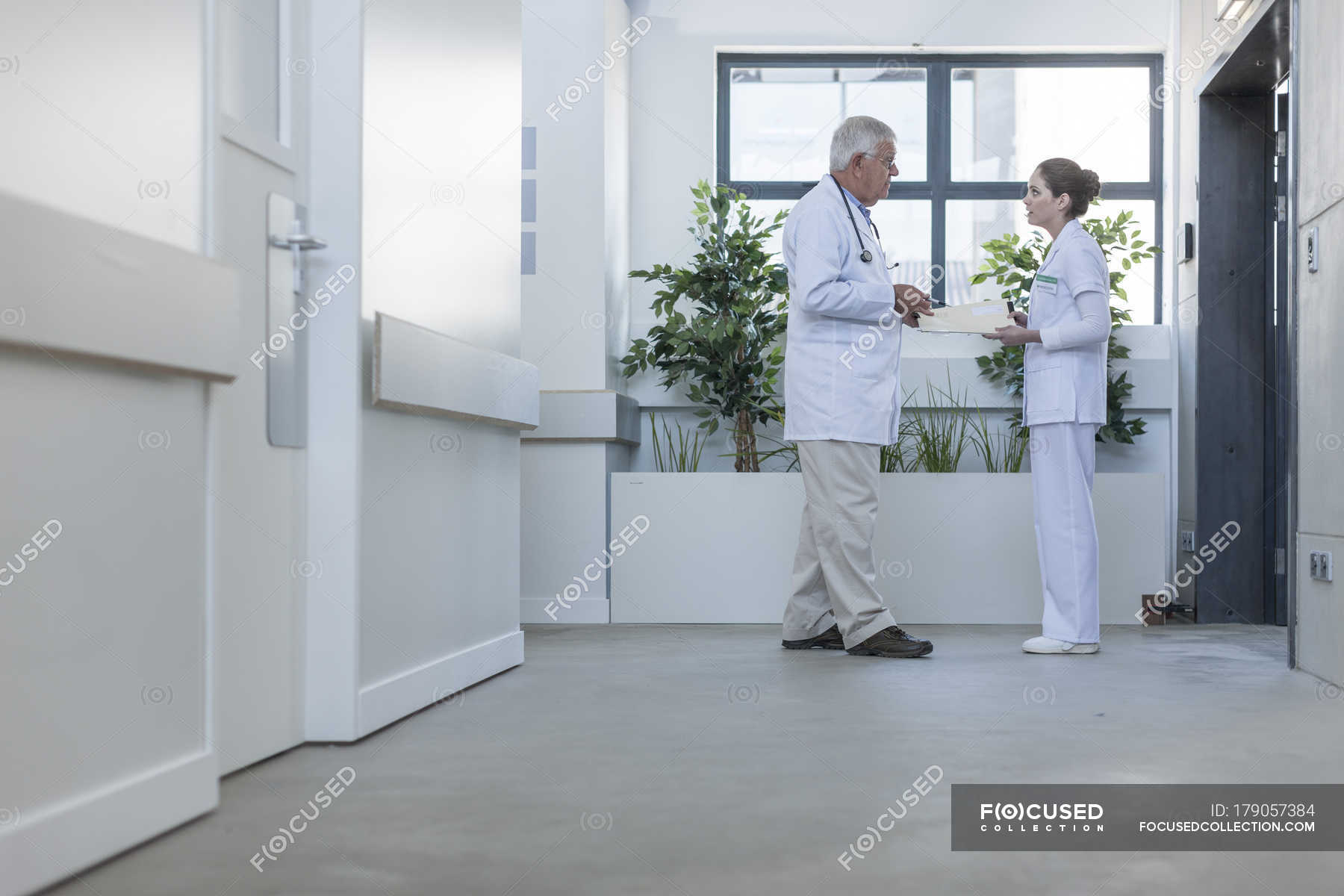 Doctor And Nurse Talking In Hospital Corridor — Together Standing