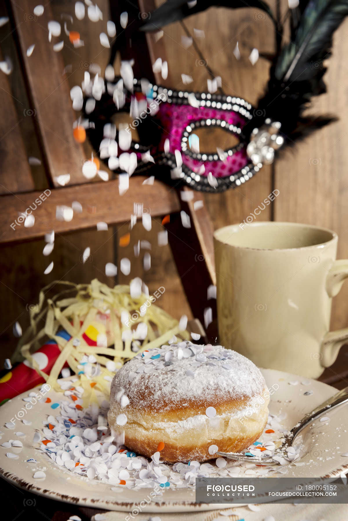 Bismarck doughnut, confetti and carnival mask — motion, wooden Stock