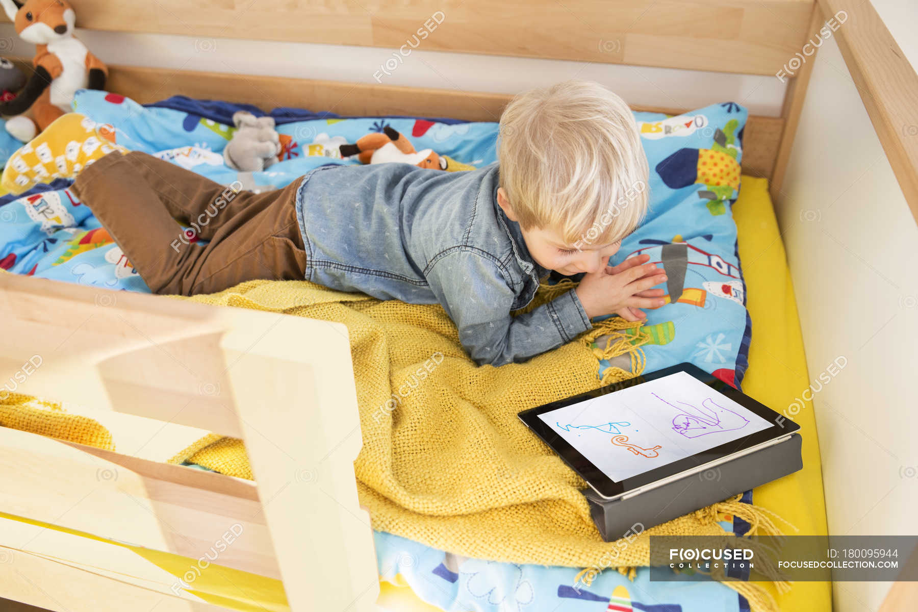 Малыш на кровати с планшетом