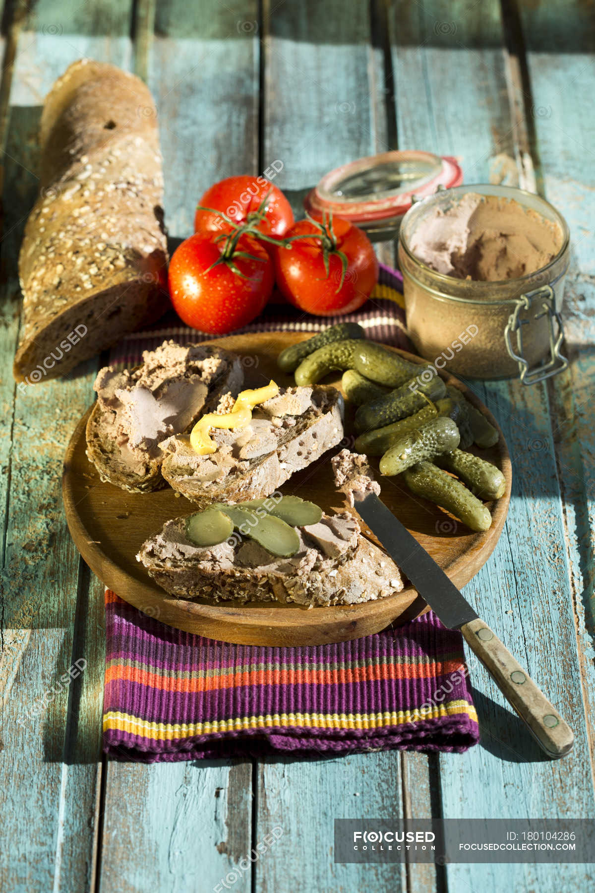 Still life of liverwurst spread with pickled cucumber and tomatoes on