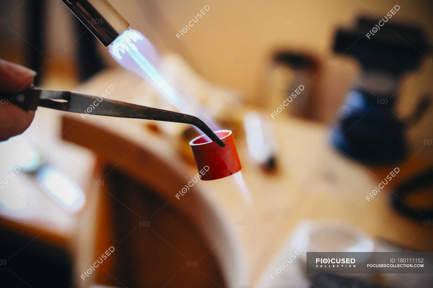 Goldsmith working with Bunsen burner on workpiece — wedding ring, woman