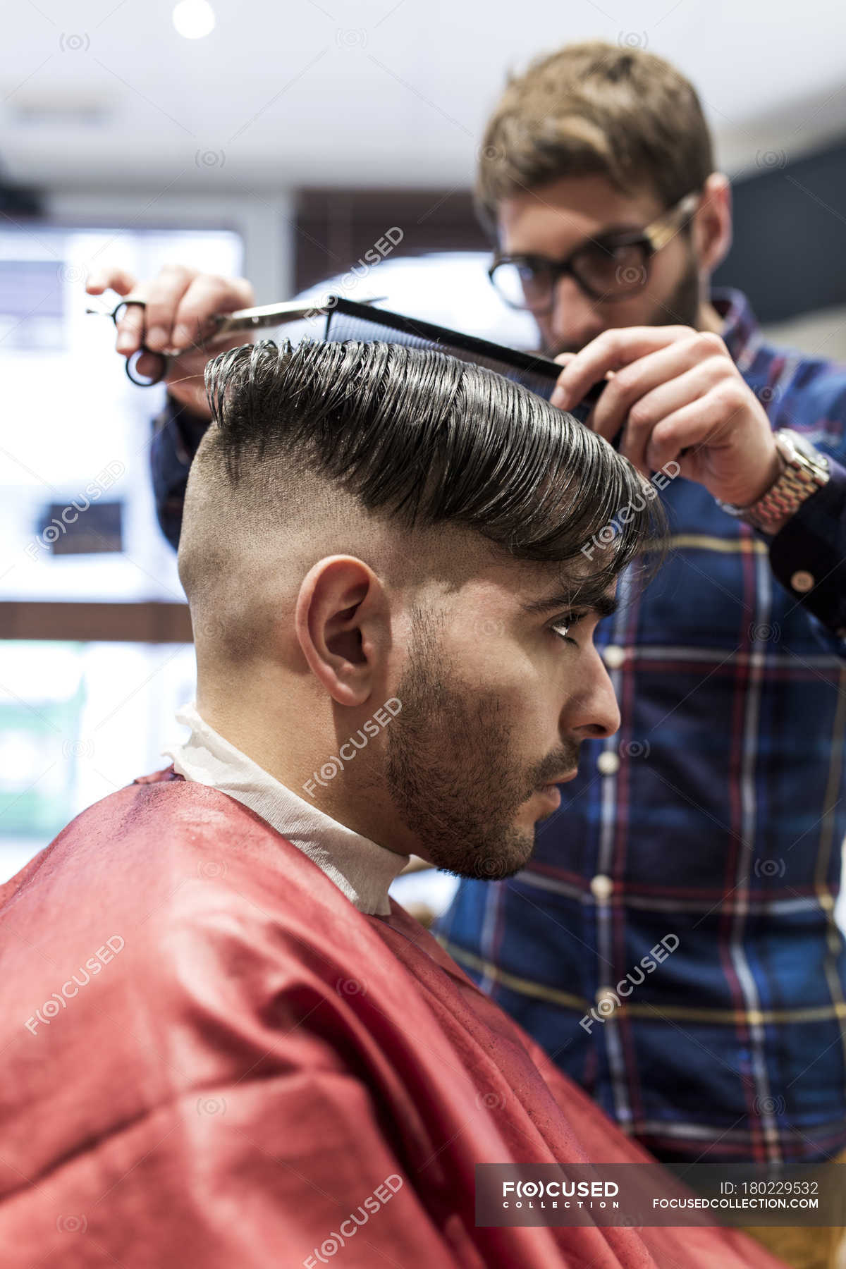 Hairdresser cutting young man's hair in a barbershop — hair salon, scissors  - Stock Photo | #180229532