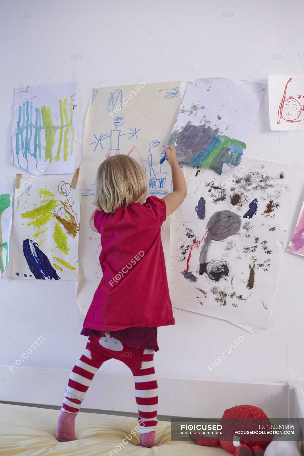 little-girl-painting-on-wall-of-children-s-room-rear-view-pen