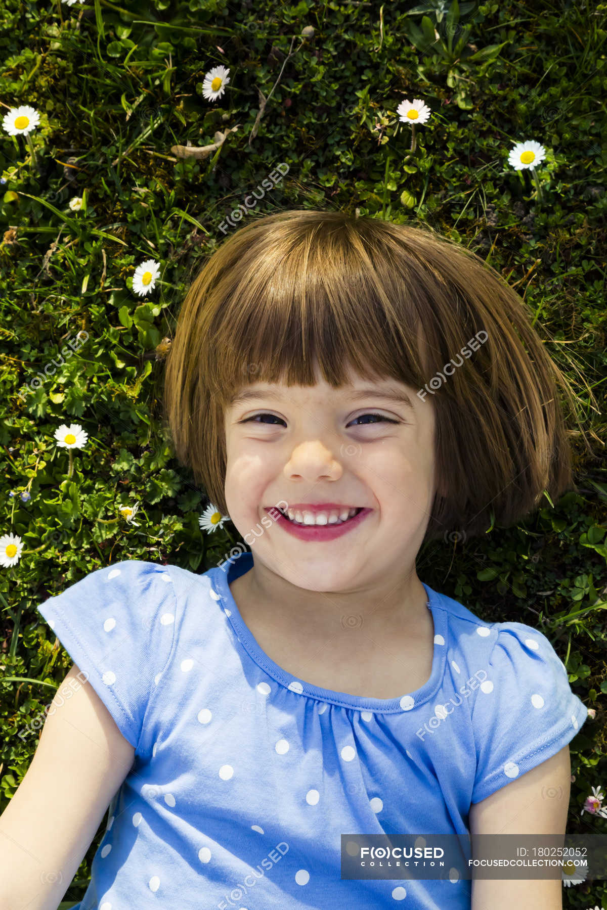 portrait-of-happy-little-girl-lying-on-a-meadow-lying-on-back