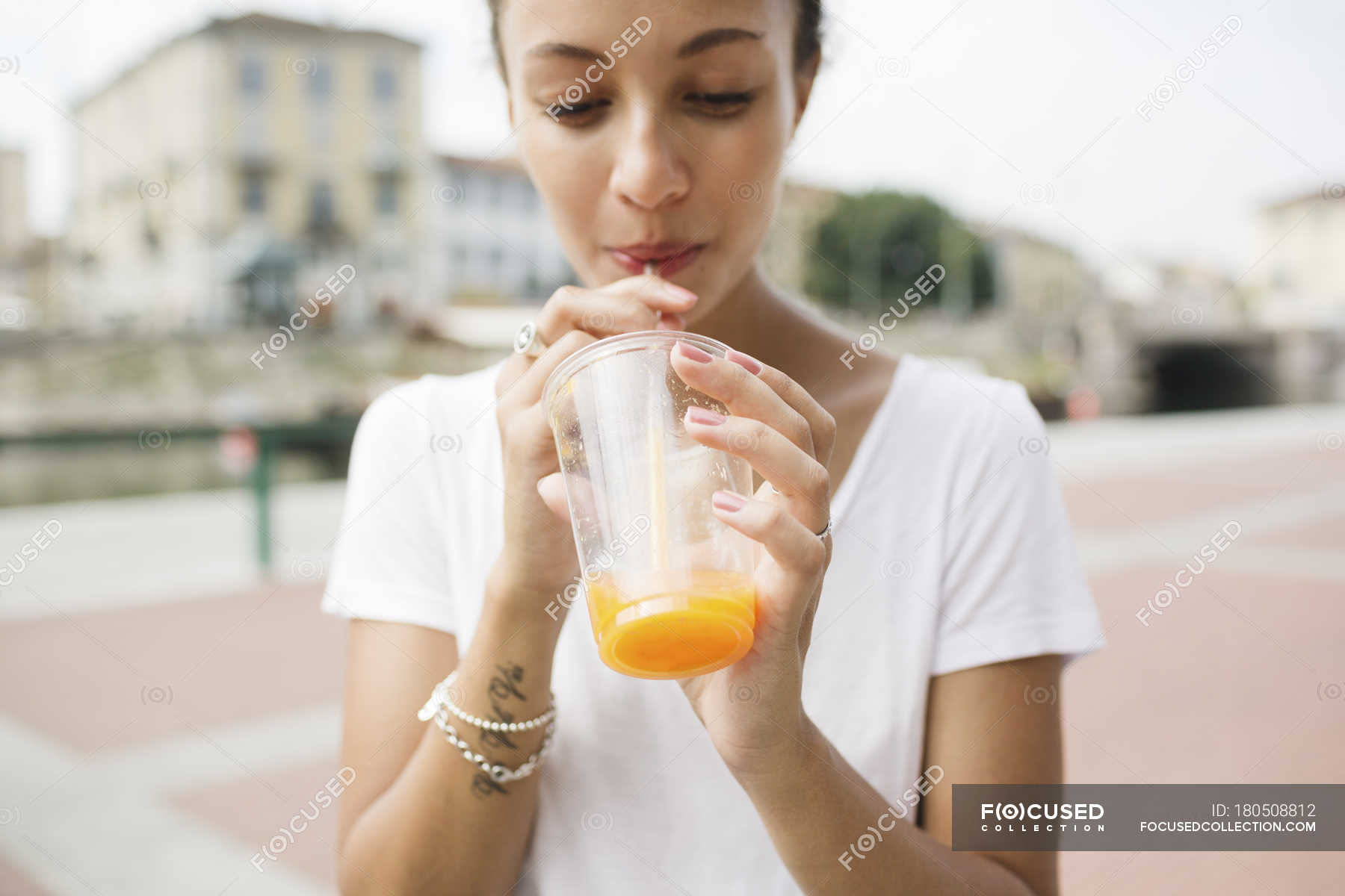 Young woman drinking orange juice with straw — cheerful, Enjoyment