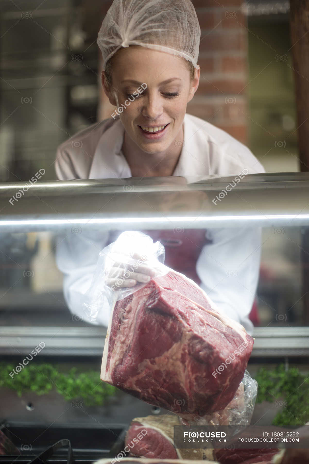 Woman putting meat on display in butchery — merchandise, close up