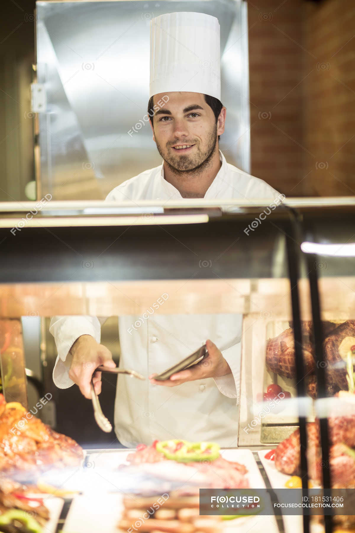 chef-serving-food-at-meat-station-young-adult-shop-stock-photo