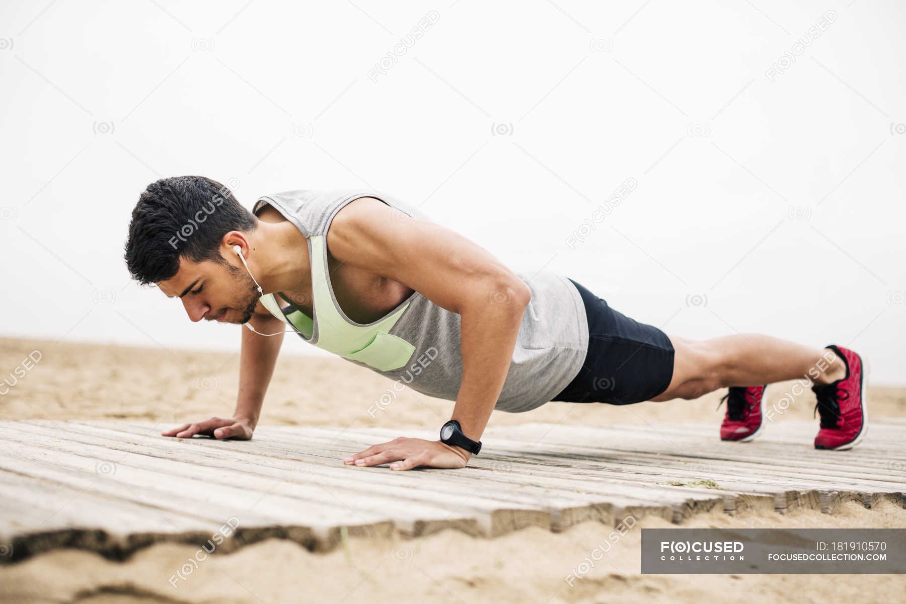 young-man-doing-push-ups-on-boardwalk-on-beach-wellness-sport