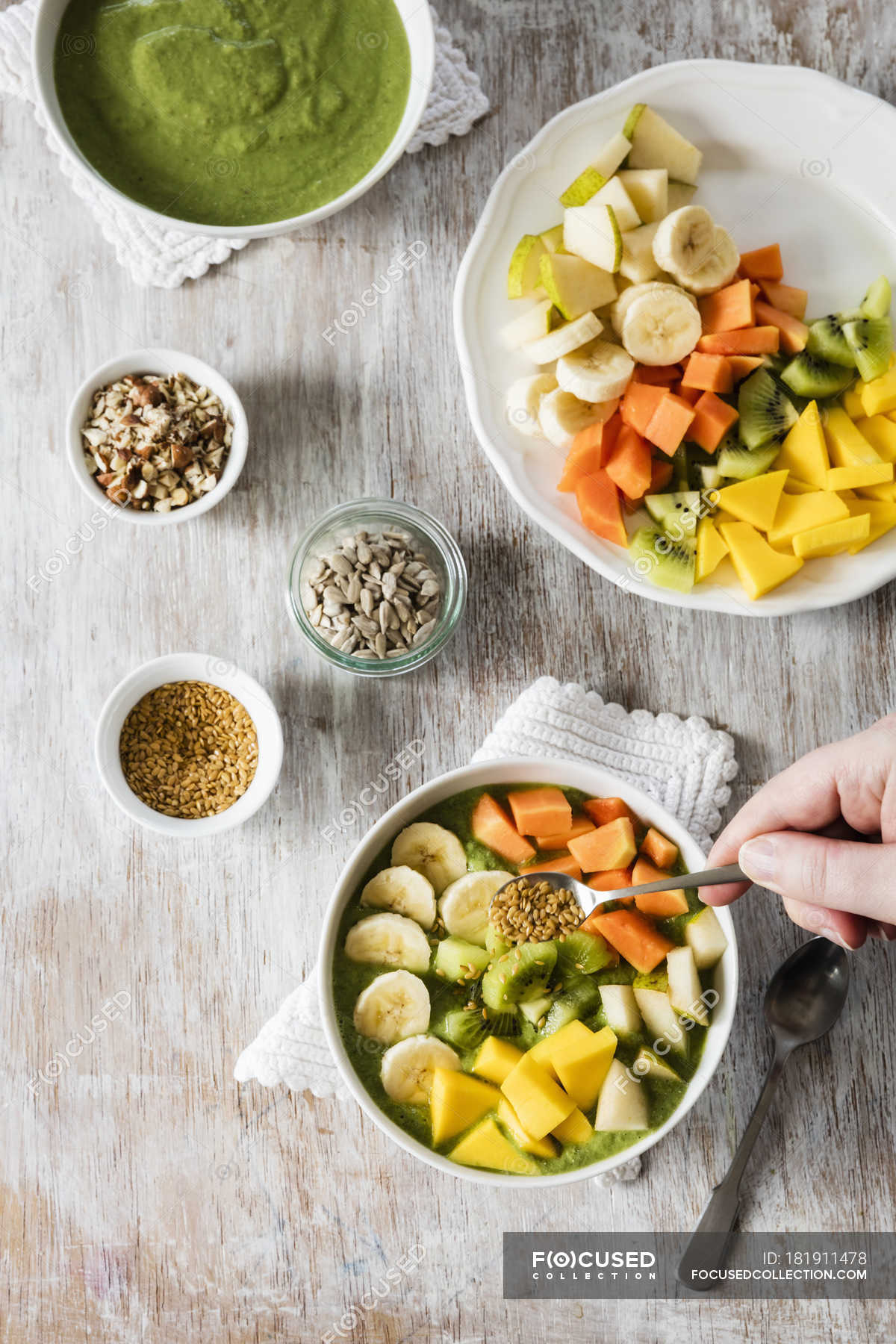 Smoothie bowl with mango, papaya, kiwi, banana, pear and toppings with  person hand — garnished, one person - Stock Photo | #181911478