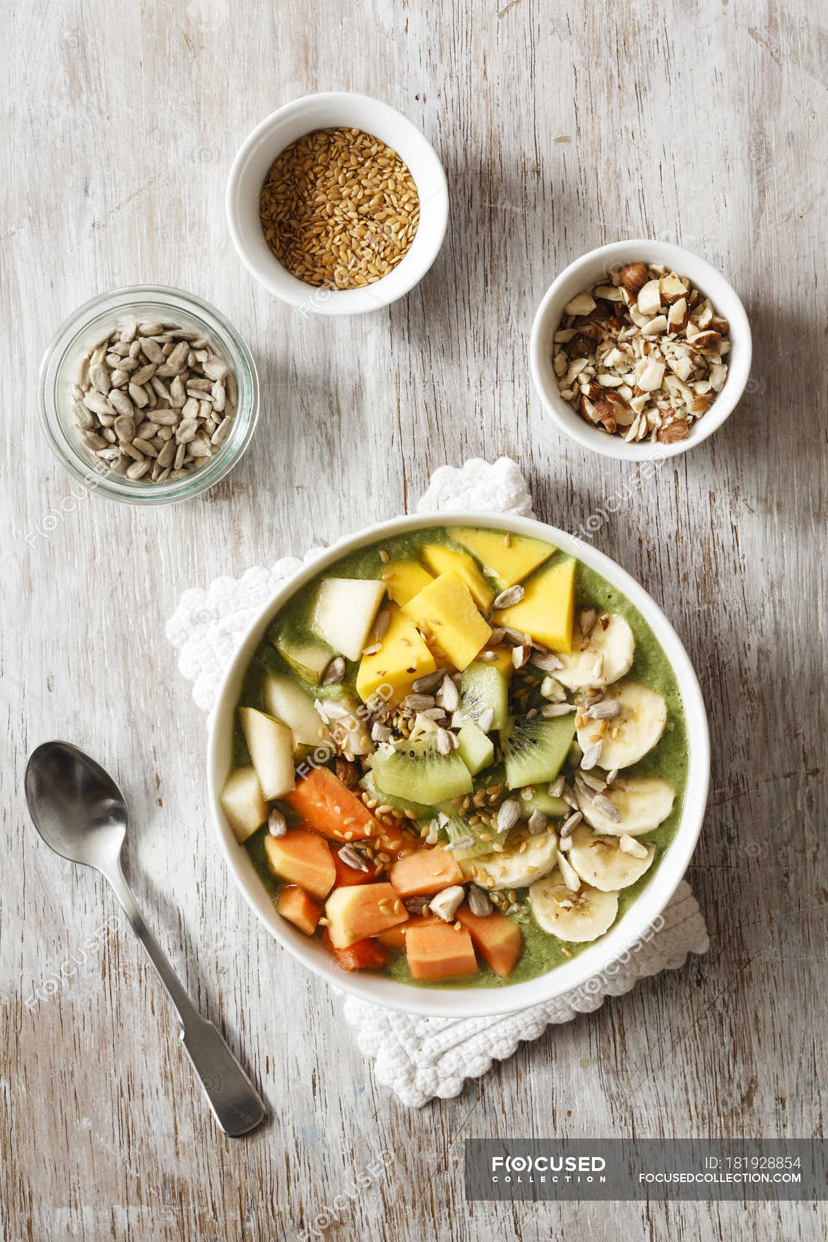 Smoothie bowl with mango, papaya, kiwi, banana, pear, lineseeds,  sunflower-seeds and nuts — organic, nutrition - Stock Photo | #181928854