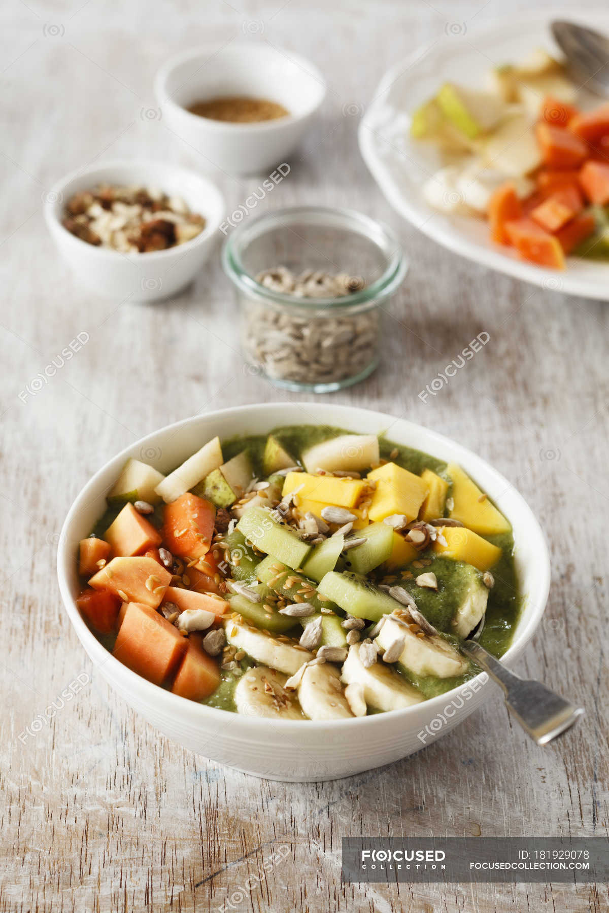 Smoothie bowl with mango, papaya, kiwi, banana, pear, lineseeds,  sunflower-seeds and nuts — vitamins, vegan - Stock Photo | #181929078