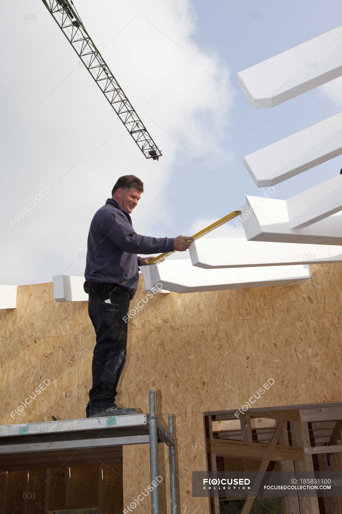 Man Working With Water Level On Construction Site Roof Mature Man Stock Photo