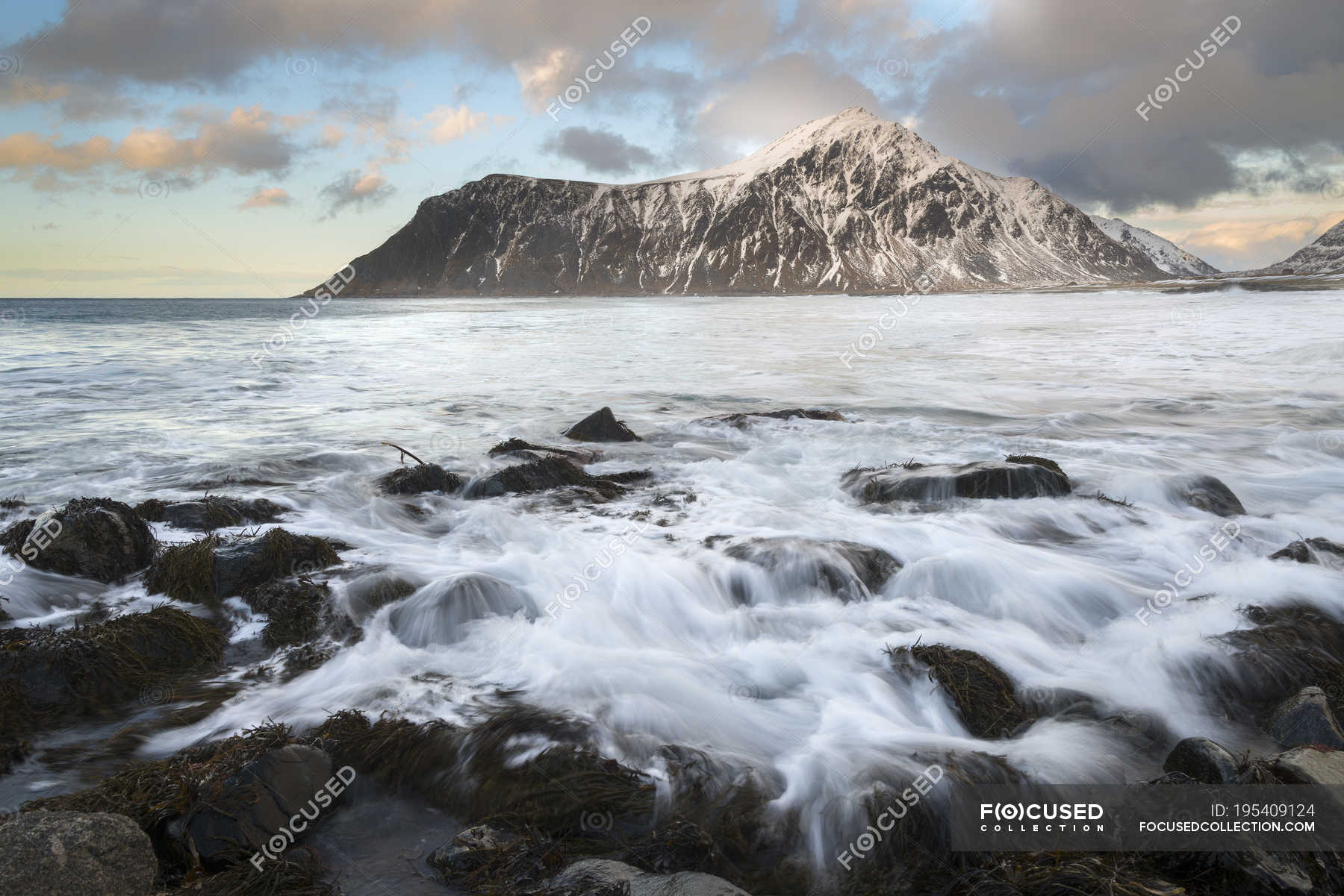 Norway Lofoten Flakstad Rocky Beach At Sunset With Mountain On Background Twilight Motion Stock Photo