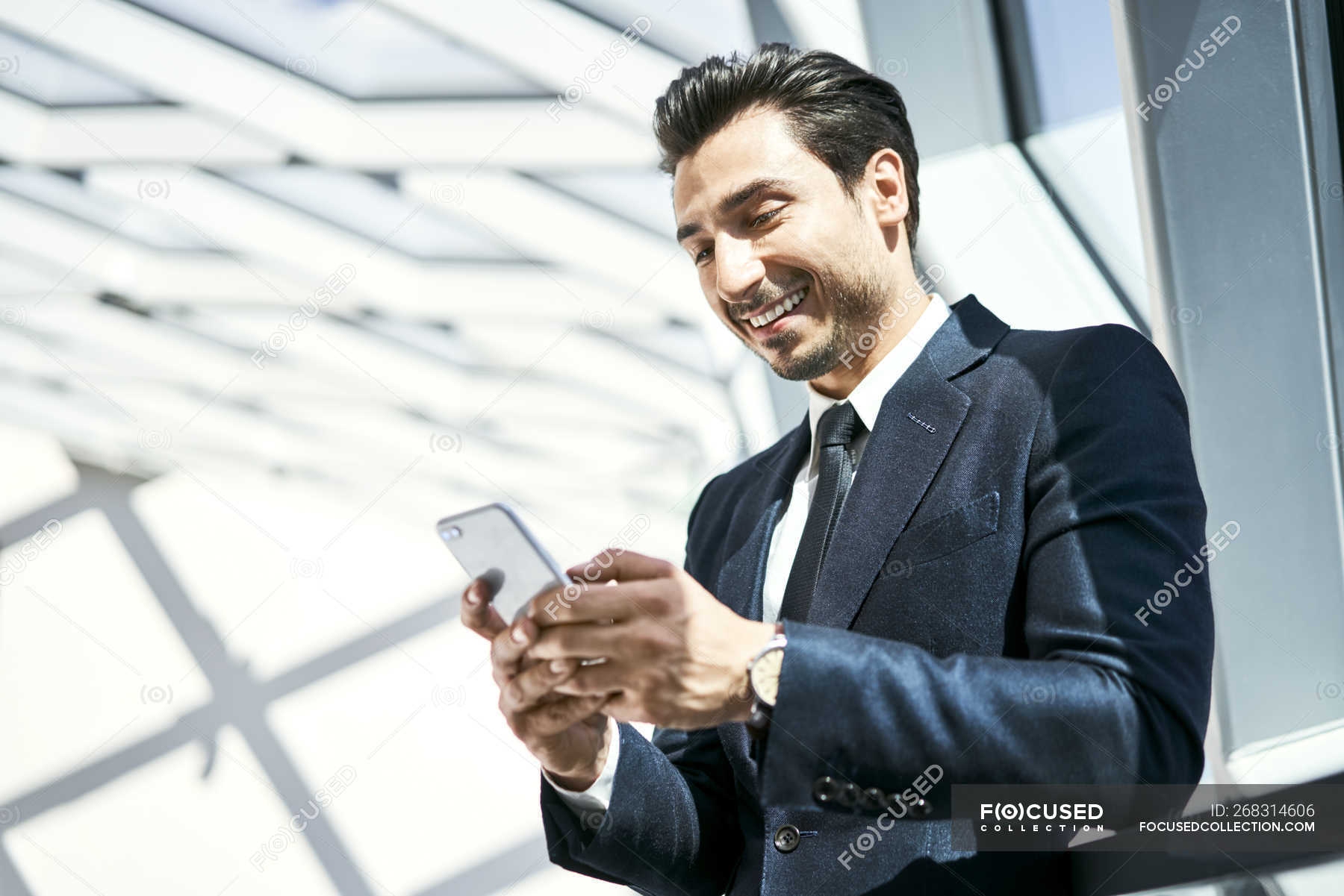 Un uomo d'affari sorridente che guarda il cellulare — guardare, Positivo -  Stock Photo