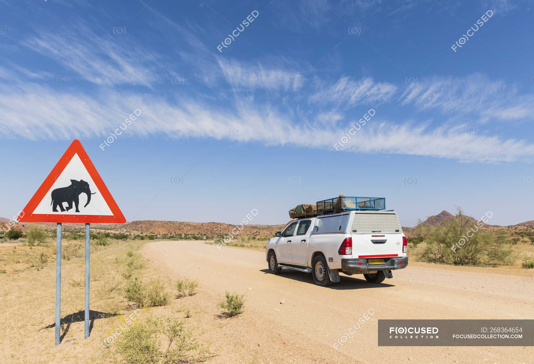 Namibia, Erongo Region, offroad vehicle on sand track, deer crossing sign with elephant