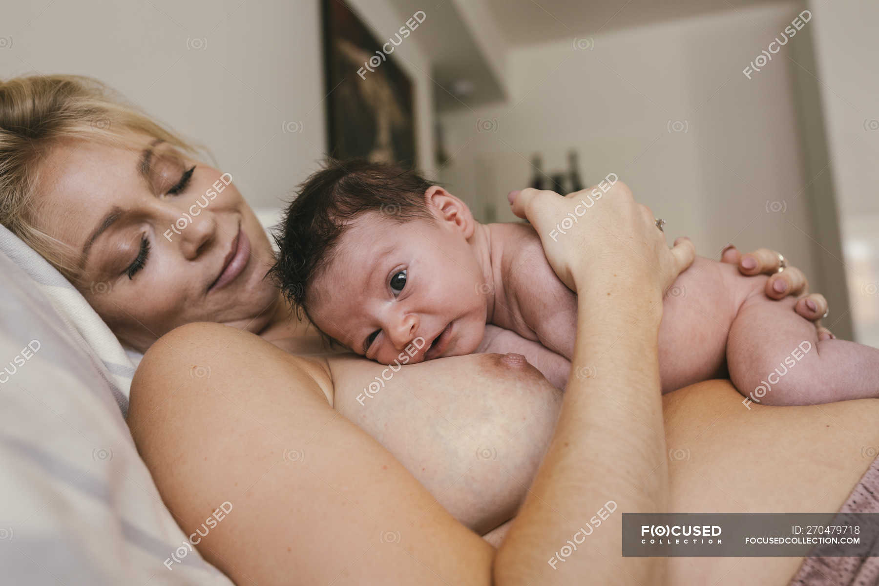 Ребенок лежит на маминых голых грудях
