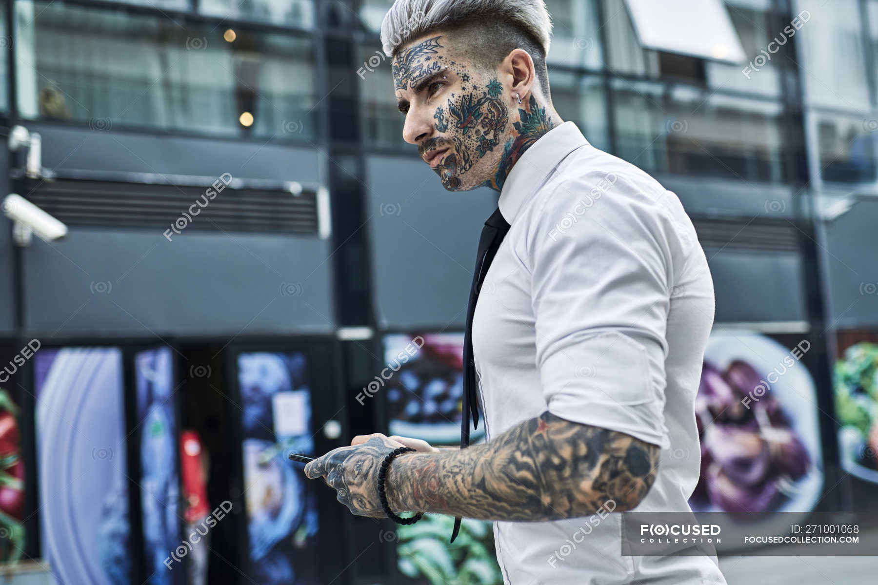 Jeune homme d'affaires au visage tatoué avec smartphone — Taille haute, non  conformiste - Stock Photo | #271001068