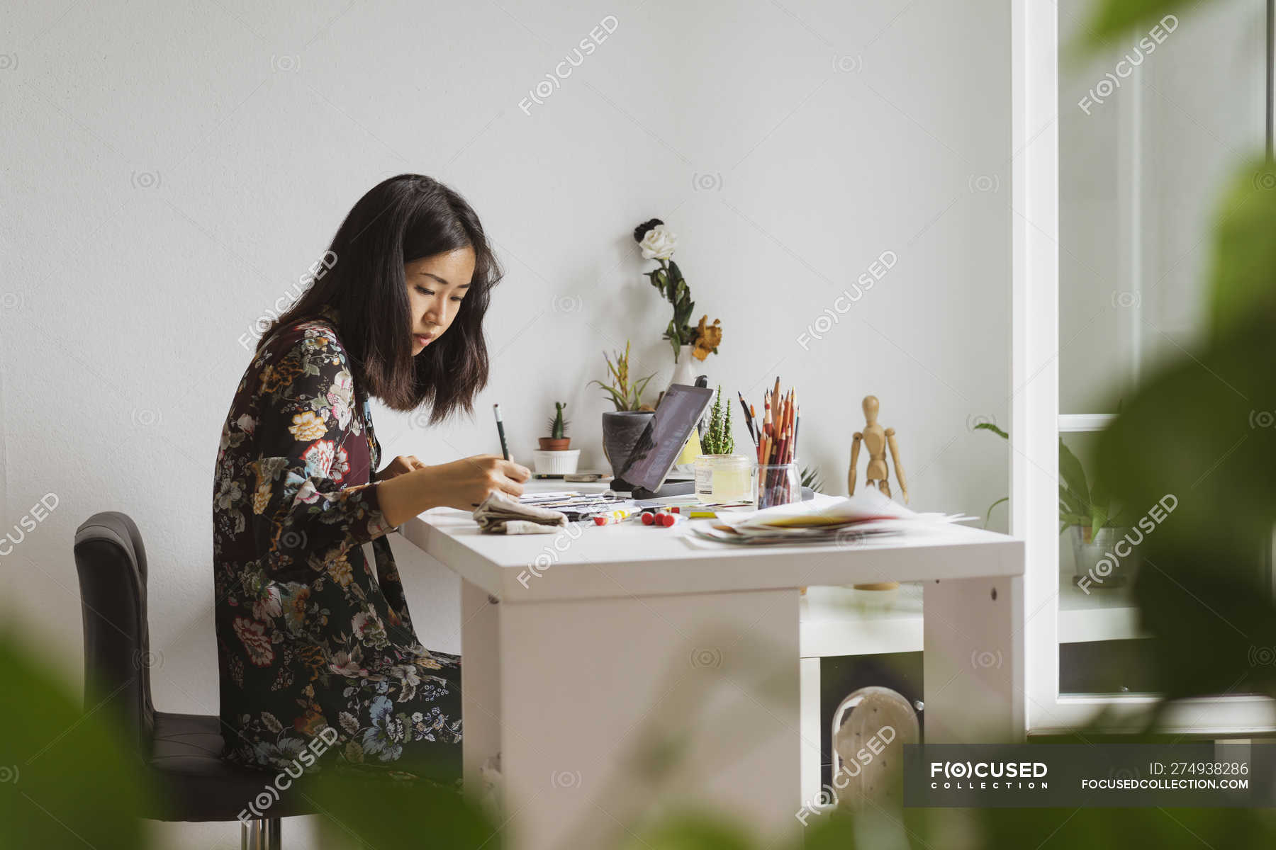 Illustrator Sitting At Work Desk In Atelier Drawing Indoors 30 40 Years Stock Photo