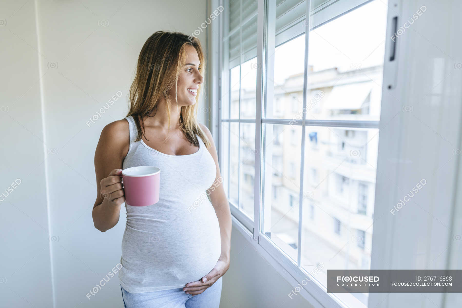 Беременная разделась и смотрит в окно
