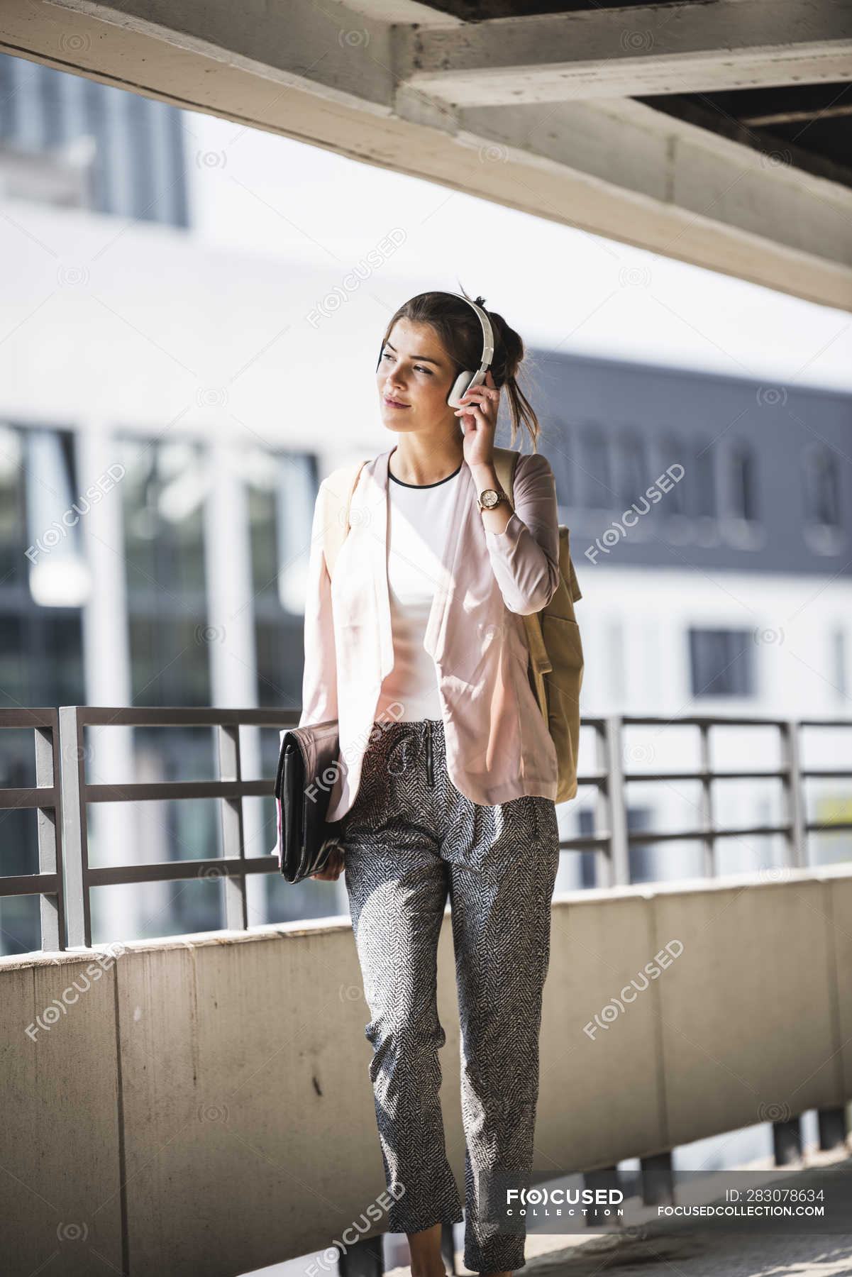 Young businesswoman walking in parking garage, listeing music with her ...