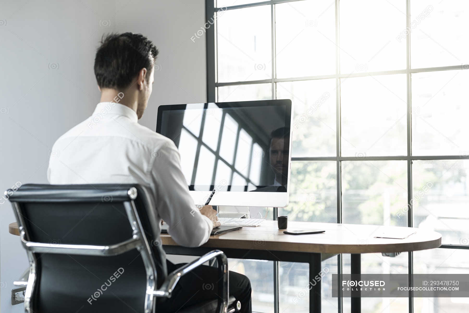 Businessman in office working on computer in front of window — sitting, 20  30 years - Stock Photo | #293478750