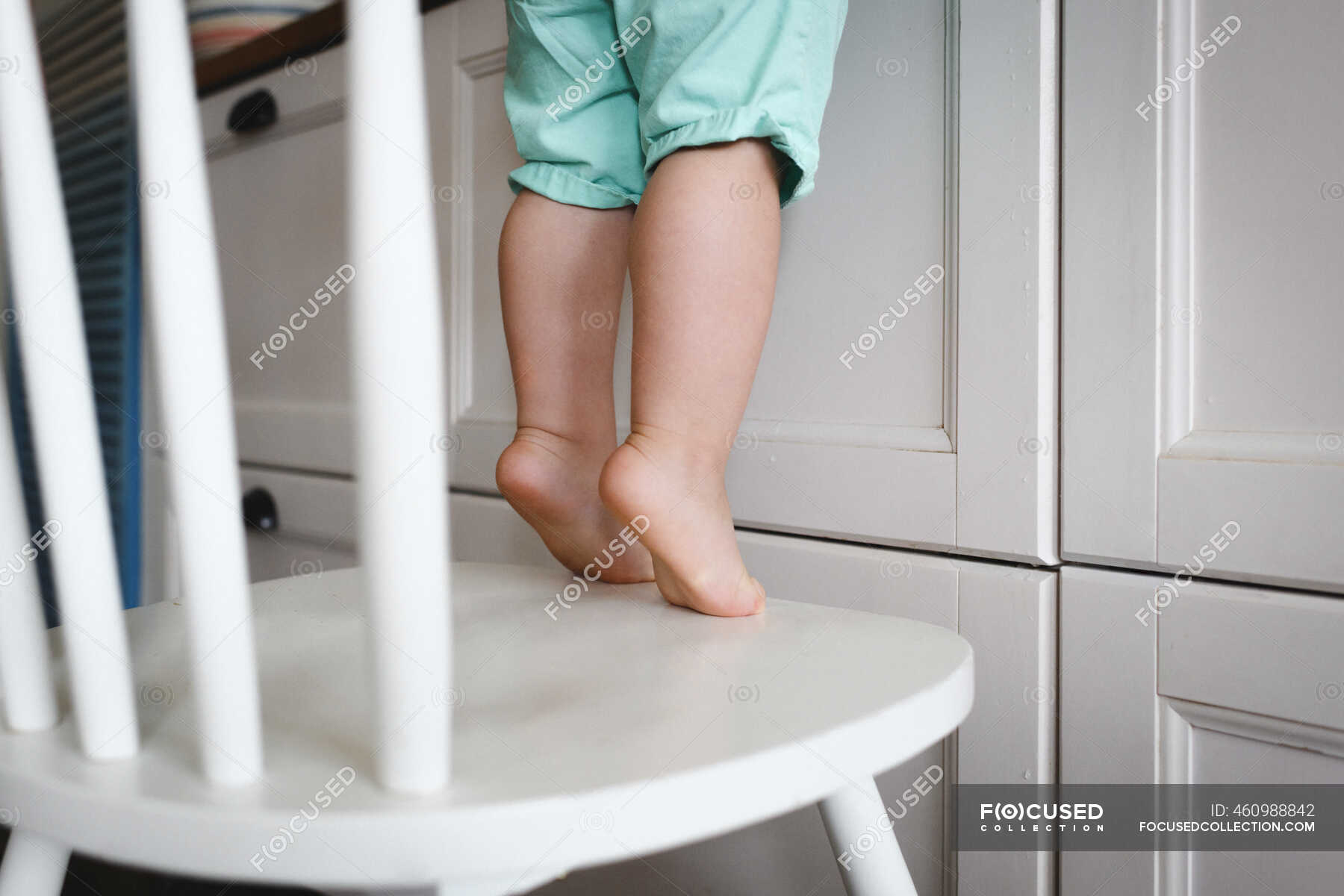 little-boy-standing-on-tiptoes-on-chair-in-kitchen-home-toddler