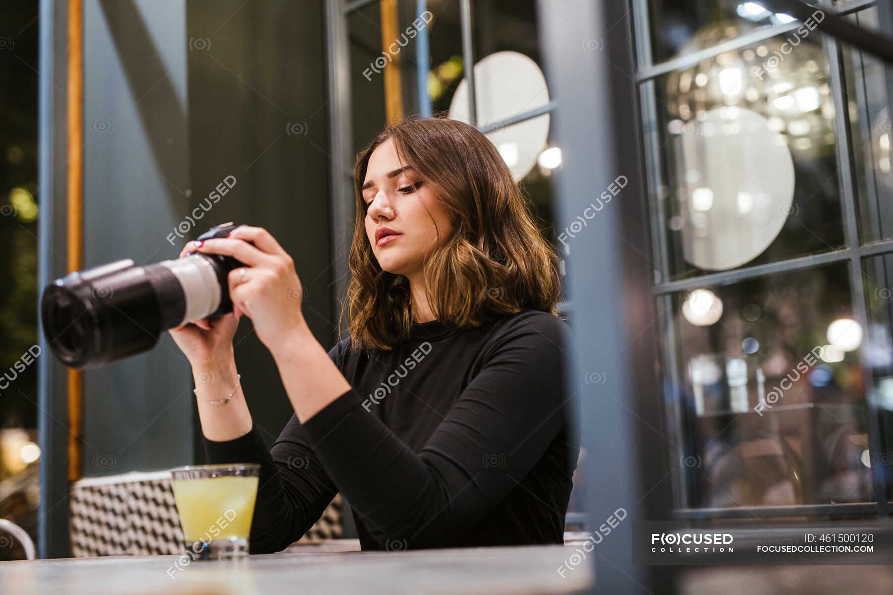 Young woman with camera in a bar at night — professional, 20 30 years