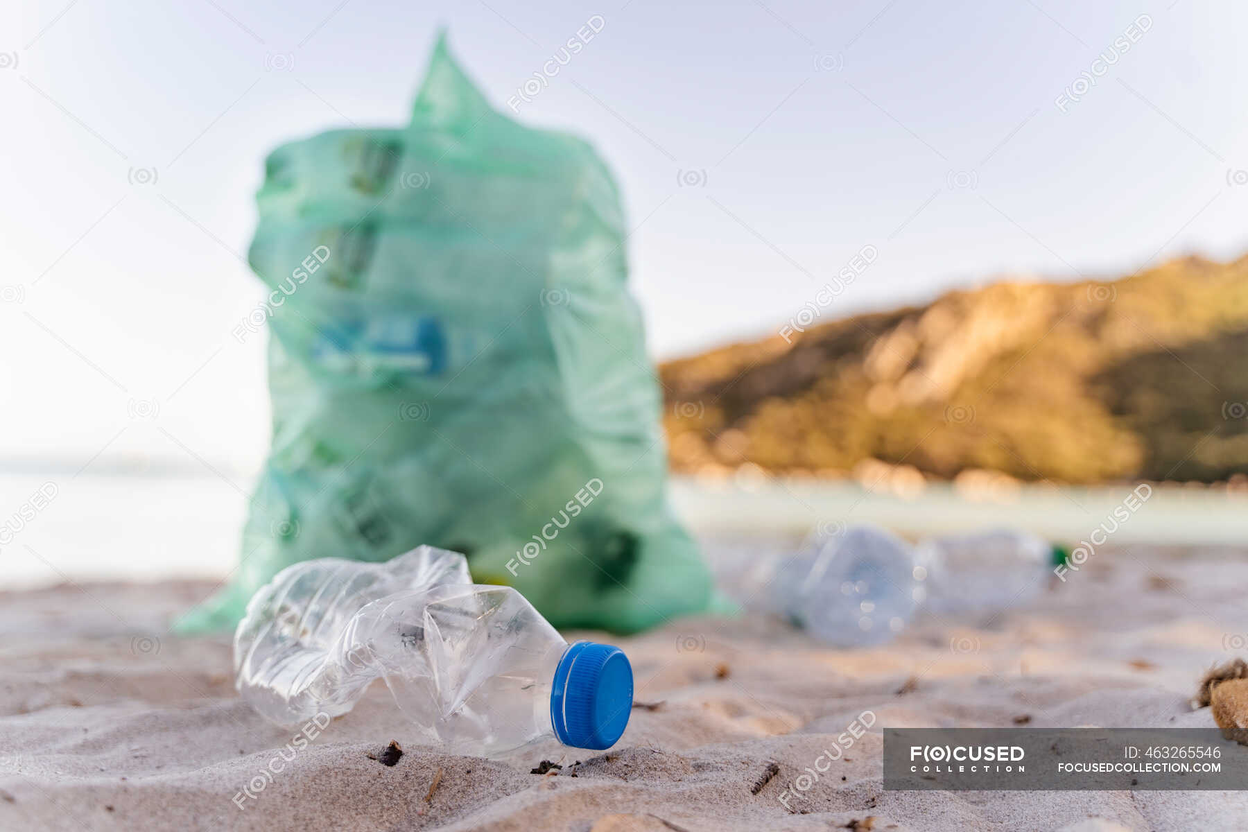 Empty plastic bottles and garbage bin full of collected plastic bottles