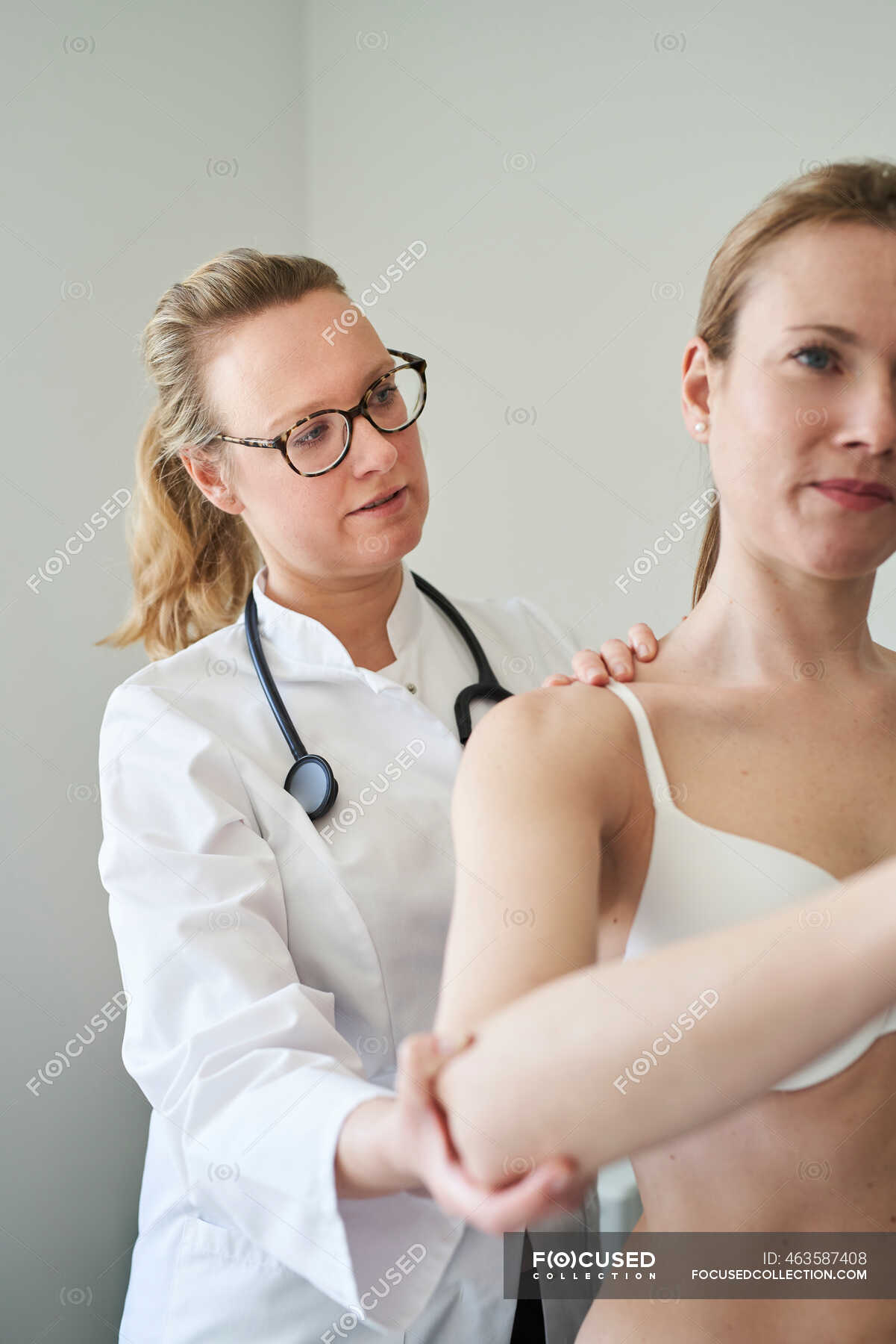 Female Doctor Examining Back Of Patient In Medical Practice