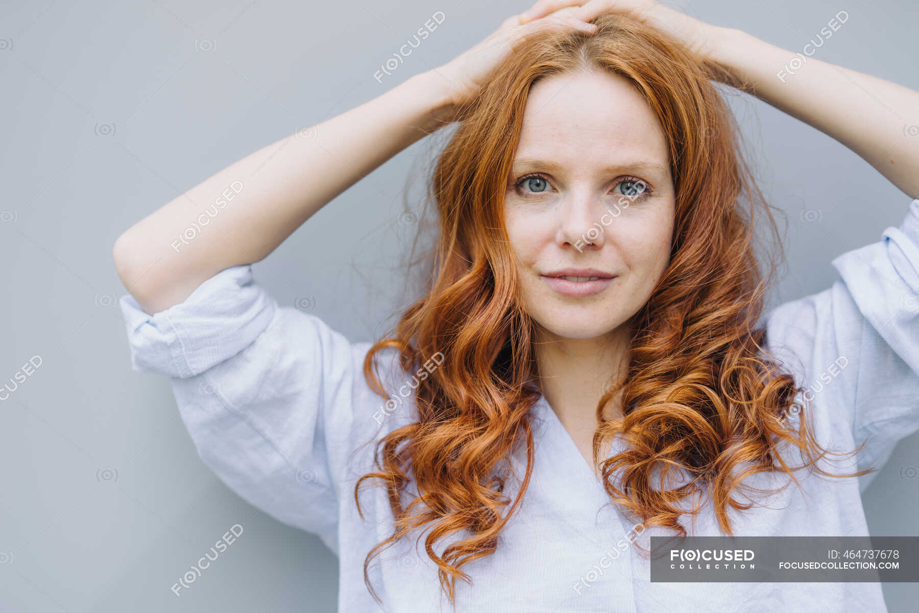 Portrait Of Beautiful Redheaded Woman At A Wall Hand In Hair Long
