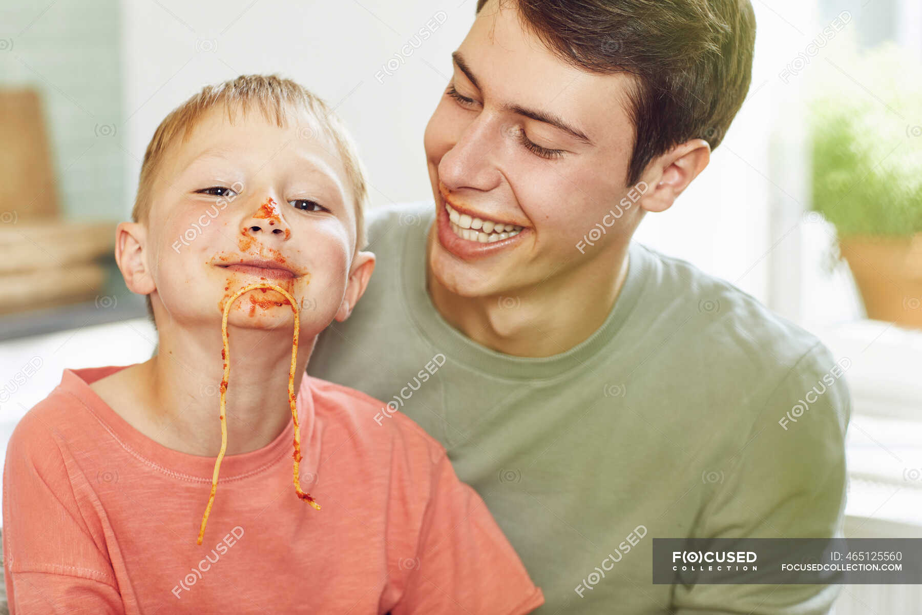 little-brother-with-face-full-of-tomato-sauce-sitting-on-lap-of-his