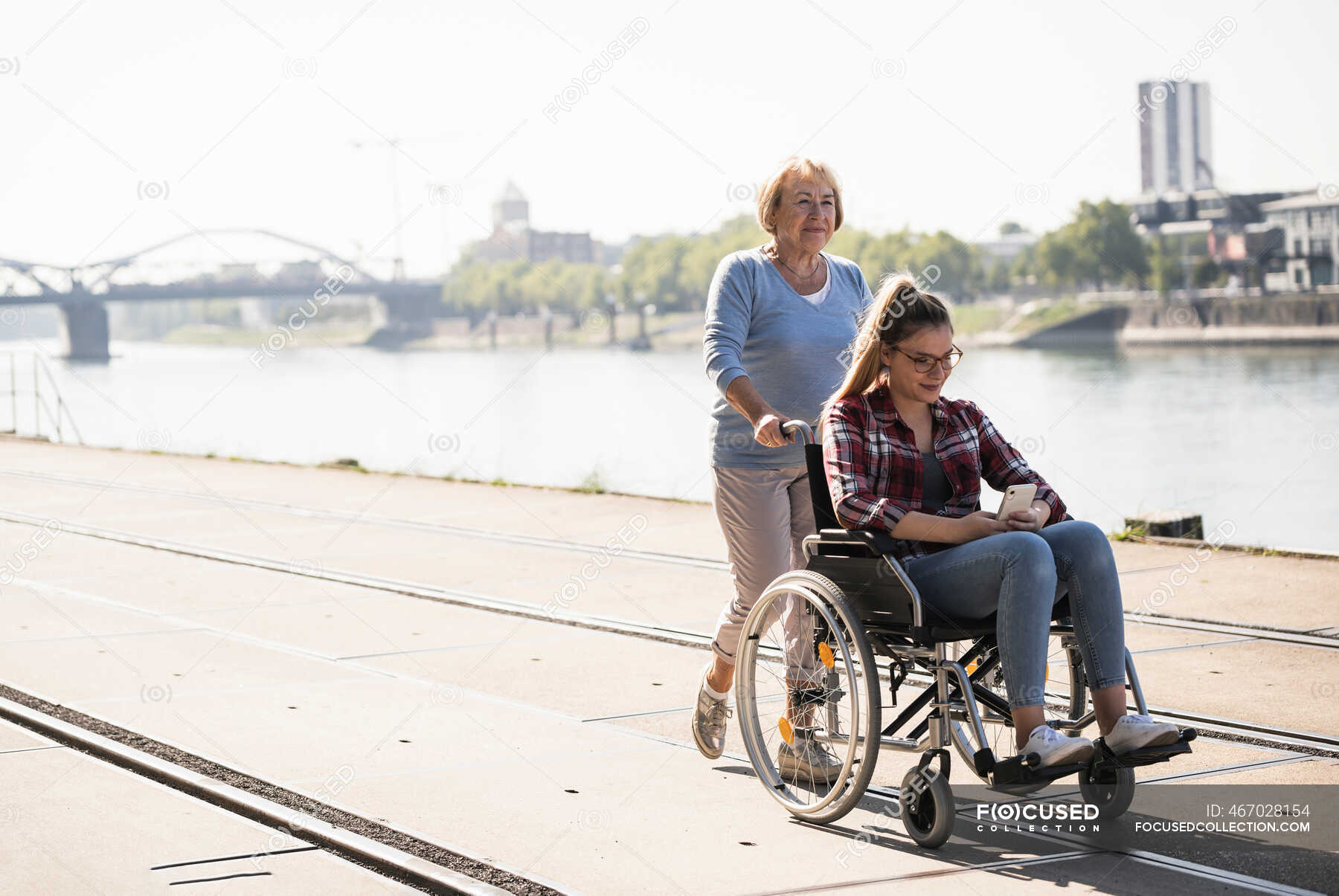 Бабушка с внучкой сидит в инвалидном кресле — технологии, радость - StockPhoto
