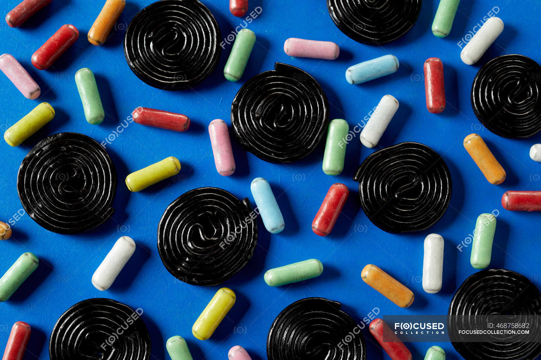 Spiral wheels of licorice candy with sugar coated licorice on blue