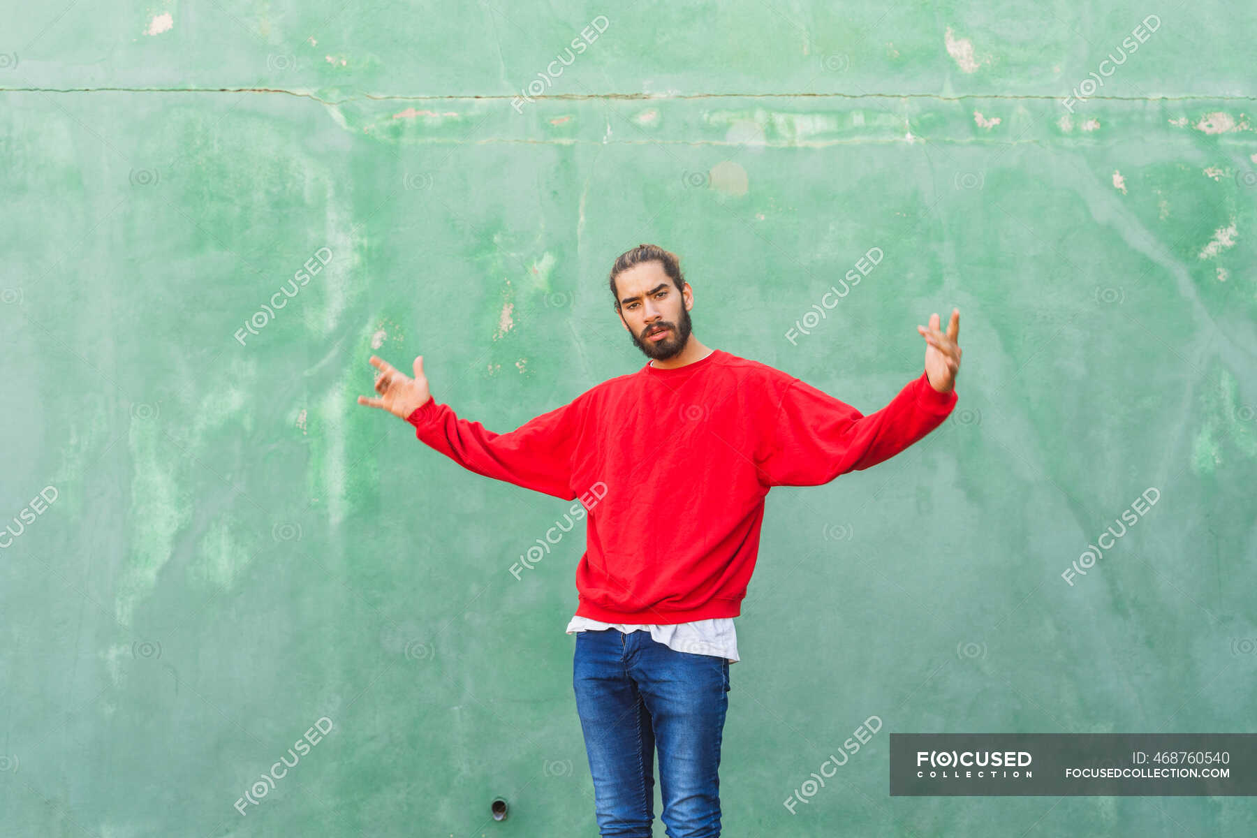 portrait-of-angry-young-man-wearing-red-sweatshirt-in-front-of-green