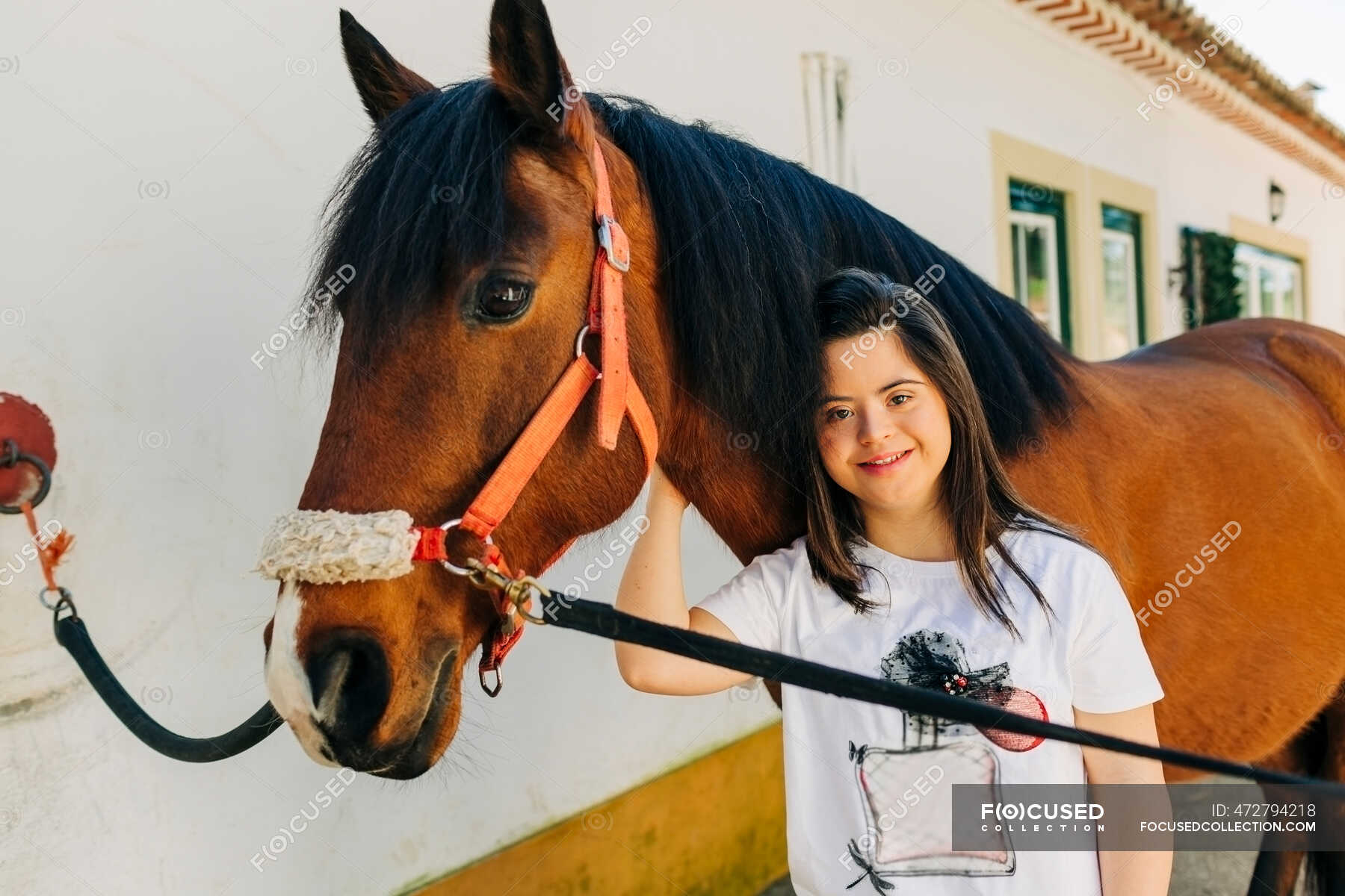 Teenager with down syndrome taking care of horse and preparing horse to