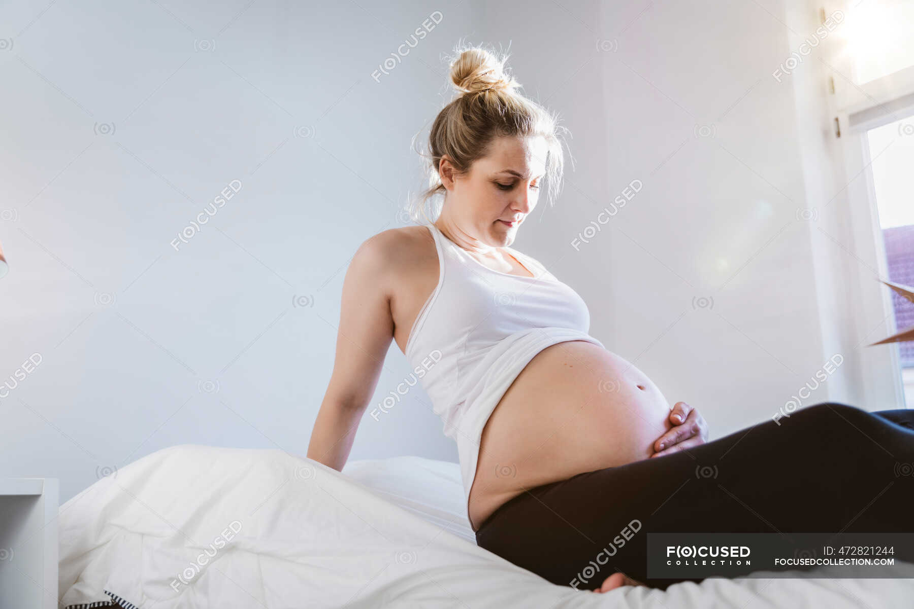 Отдых обнаженной беременной девицы на кровати