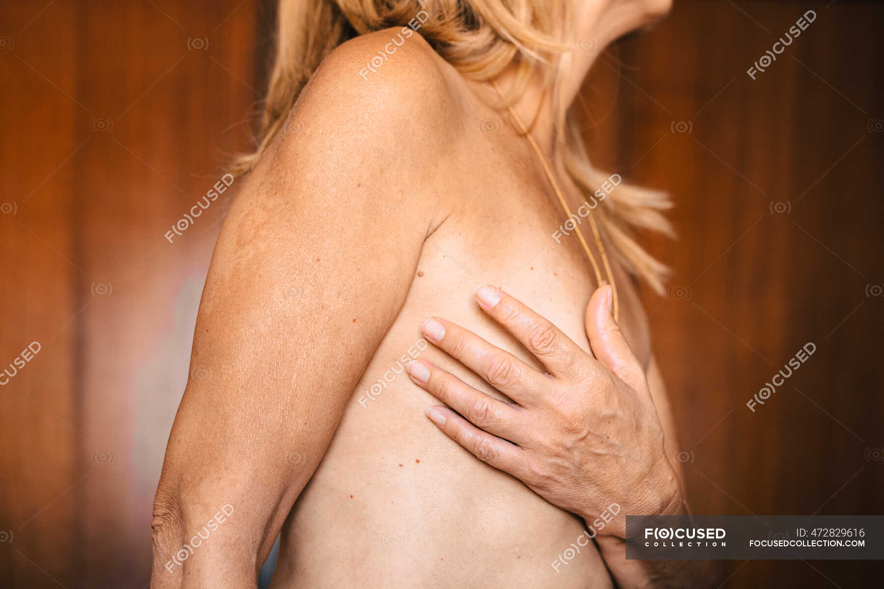 Primer plano de una mujer mayor desnuda tocándose el pecho — Examen, sensualidad
