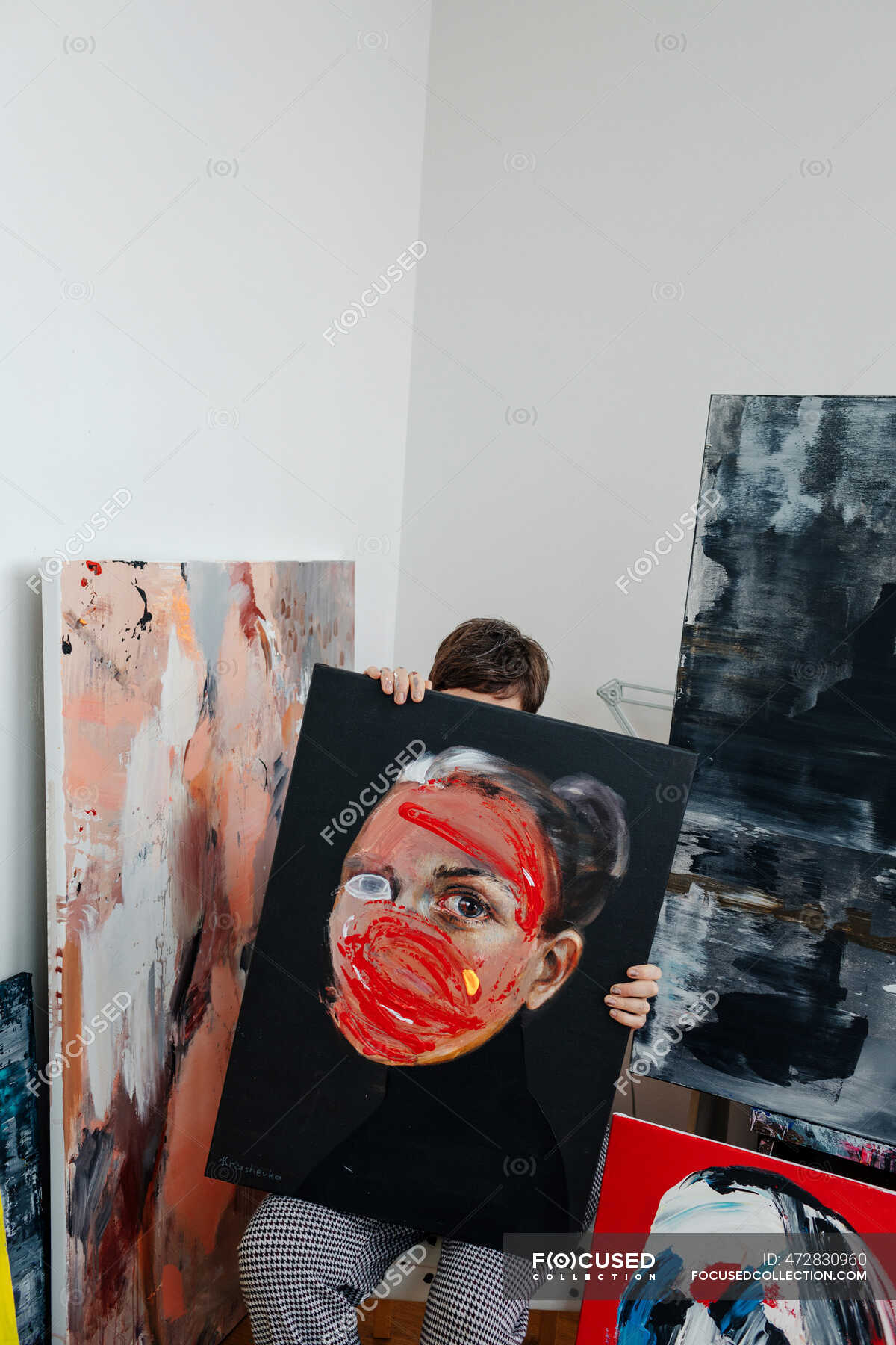 Female painter hiding behind painting in her studio — artist, obscured
